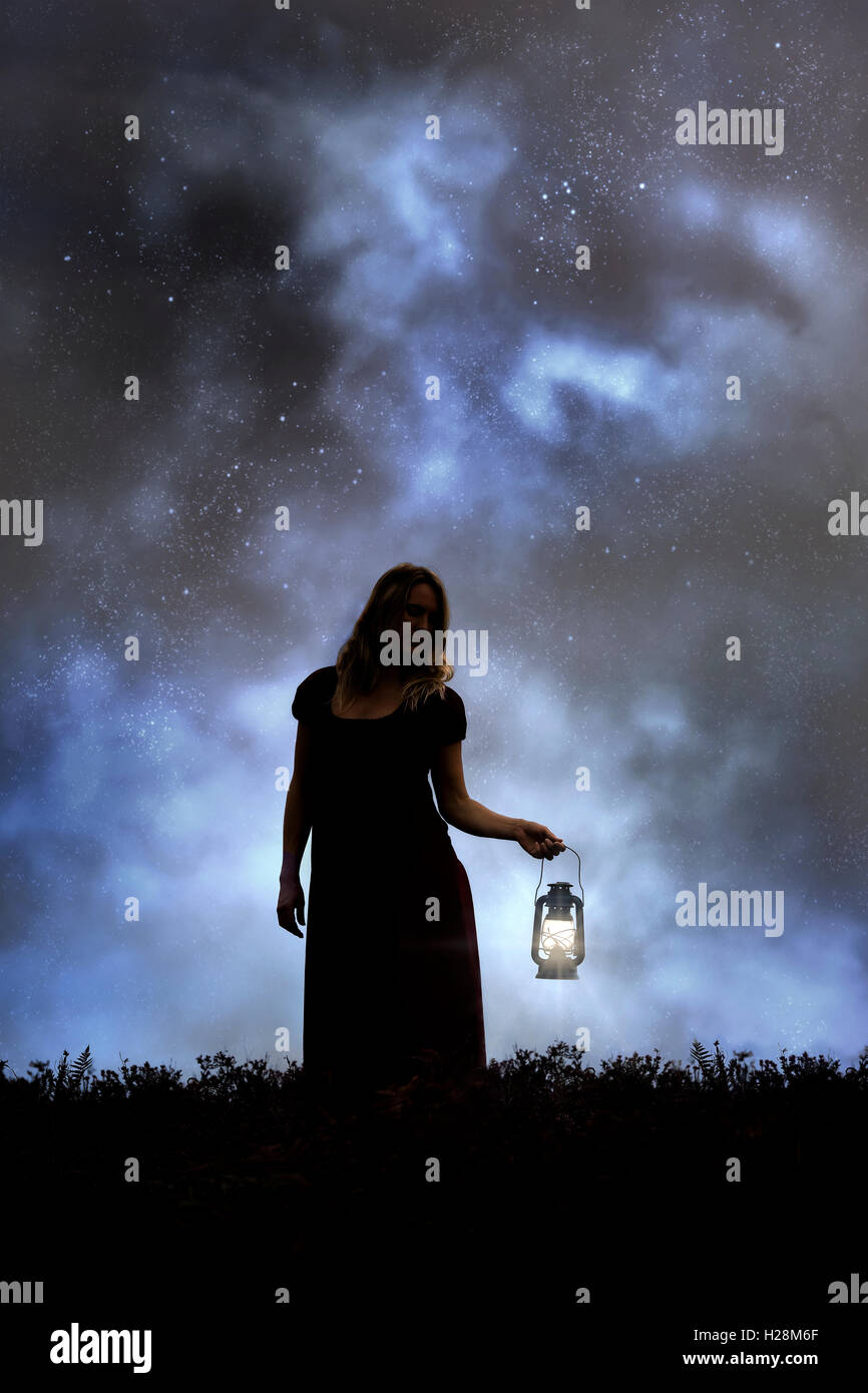 Una donna nel buio con una lanterna Foto Stock