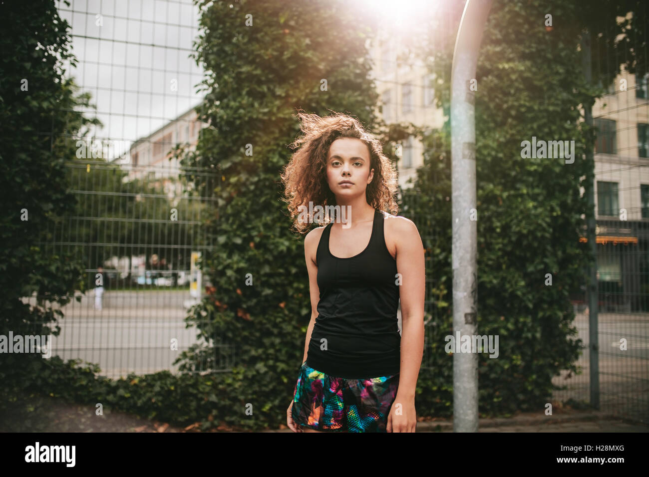 Ritratto di giovane e bella ragazza in piedi su un campo da basket e a partire da fotocamera. Hipster in casuals. Foto Stock