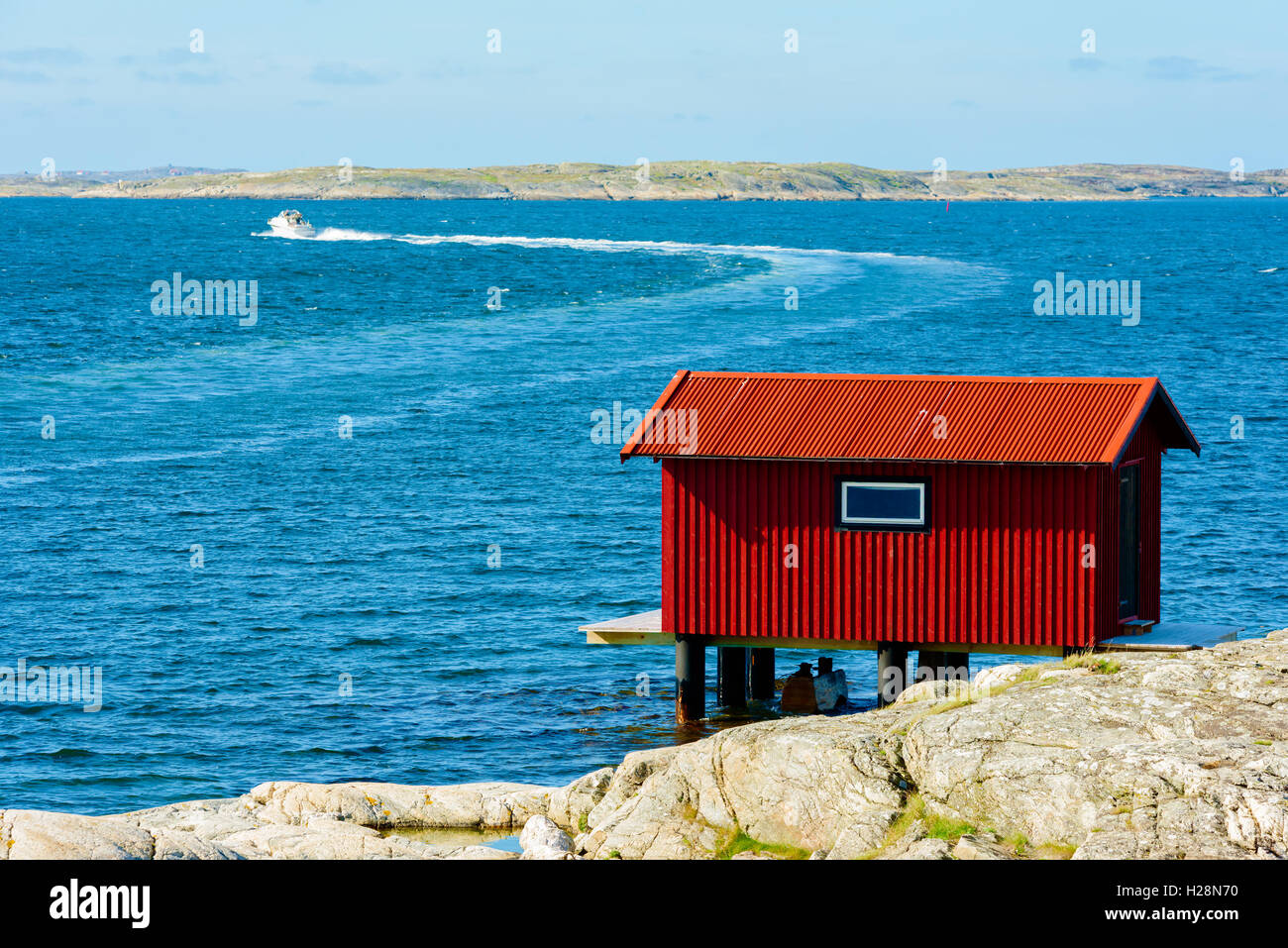 Mollosund, Svezia - 9 Settembre 2016: ambientale documentario di red boathouse su palafitte con il motoscafo facendo un giro in Foto Stock