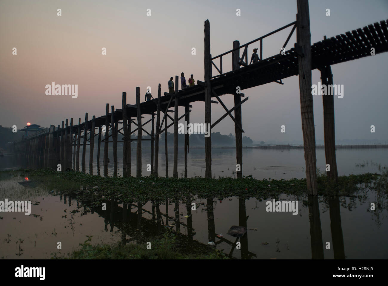 Le persone che attraversano la U Bein ponte all'orario di alba, Amarapura, Myanmar. Foto Stock