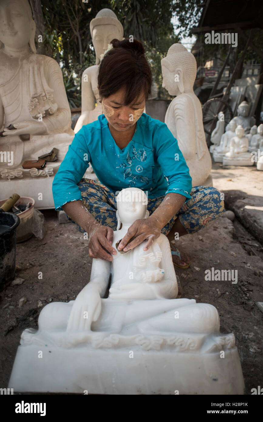 Una donna locale pulisce e lucida il marmo statue di Buddha nella sua officina, Amarapura, Myanmar. Foto Stock