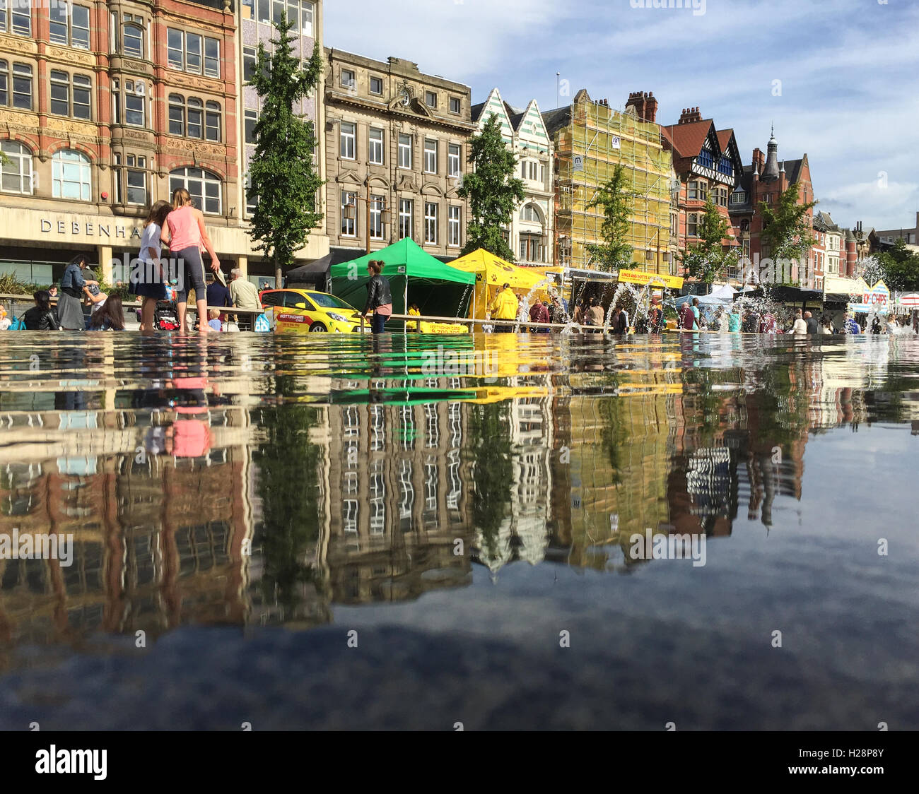 Le ragazze a giocare in acqua, varie bancarelle del mercato dietro nella piazza del mercato di Nottingham City Centre Foto Stock