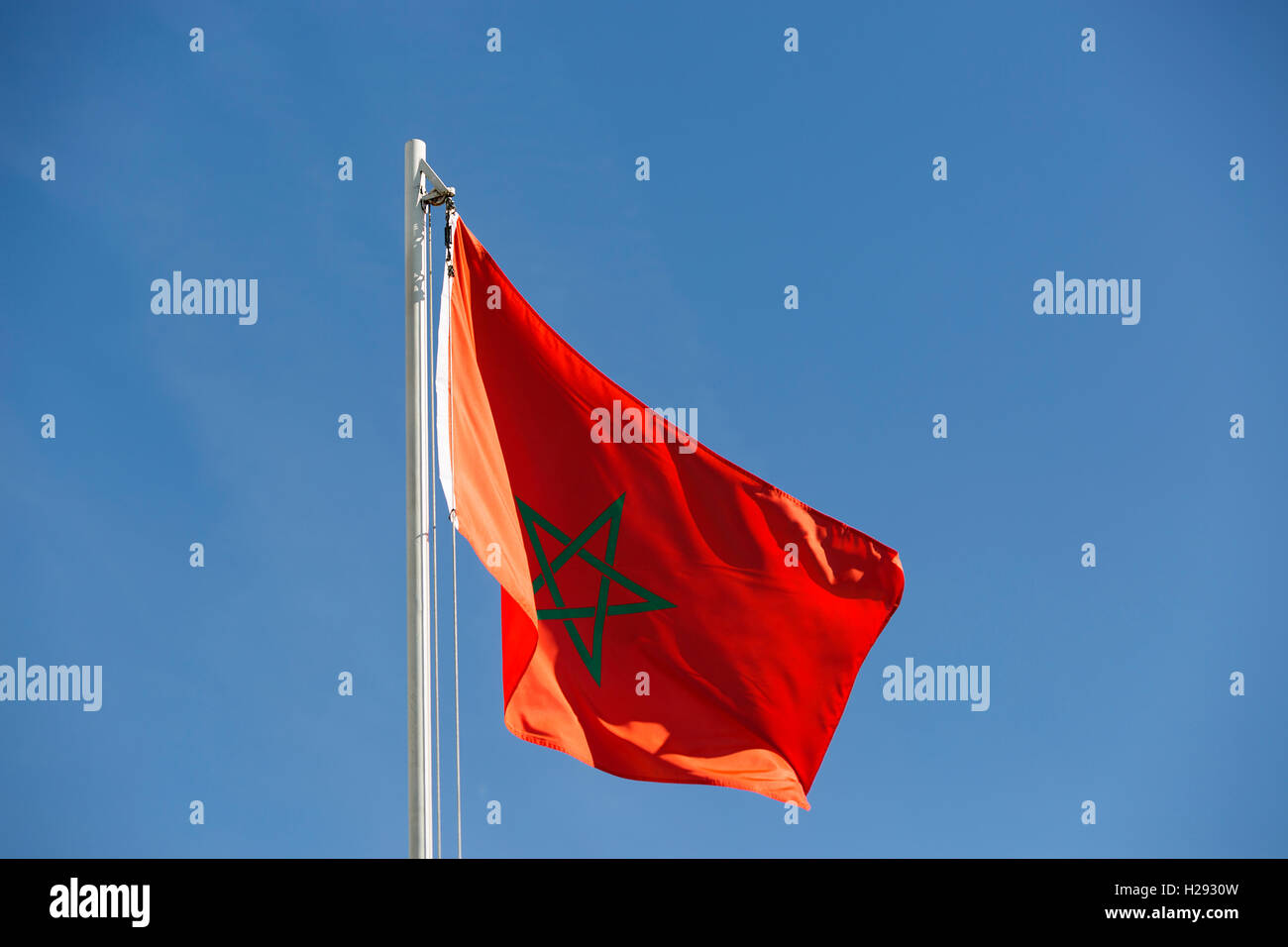 Bandiera nazionale del Marocco su un pennone di fronte blu cielo Foto Stock