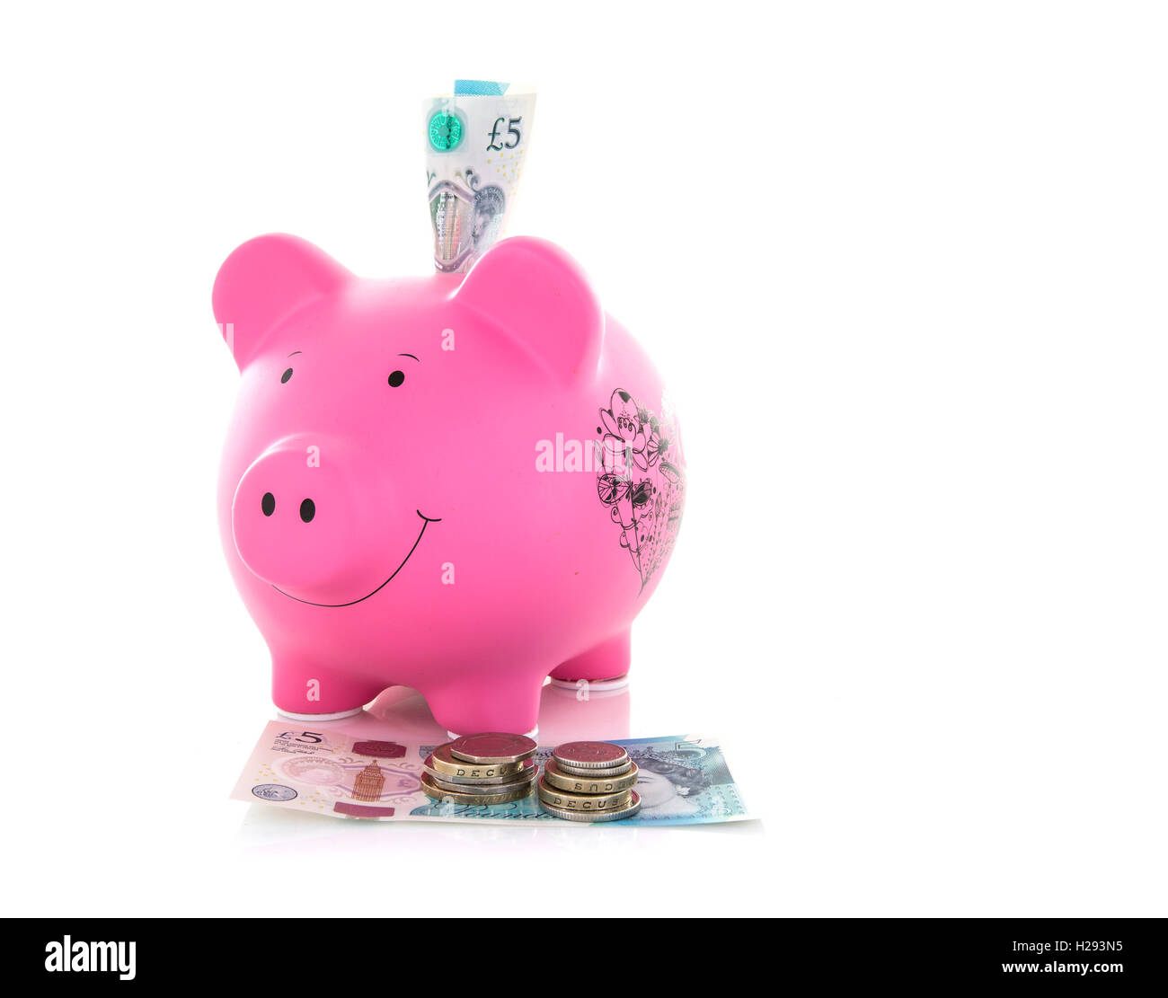 Rosa Salvadanaio con nuovo 5 libbra di monete e banconote a sfondo bianco Foto Stock
