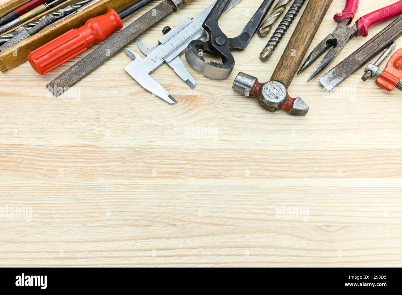 Vari vecchi utensili a mano comprendente un martello, pinze, cacciaviti e altri sul tavolo di legno sfondo Foto Stock
