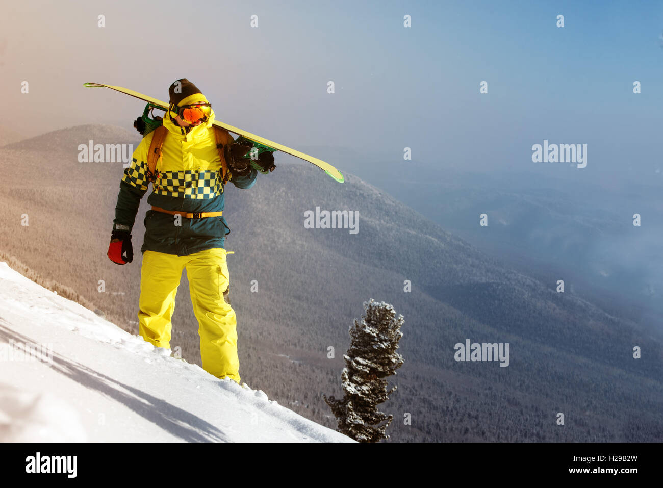 Snowboarder in posa sul cielo blu sullo sfondo di montagne Foto Stock