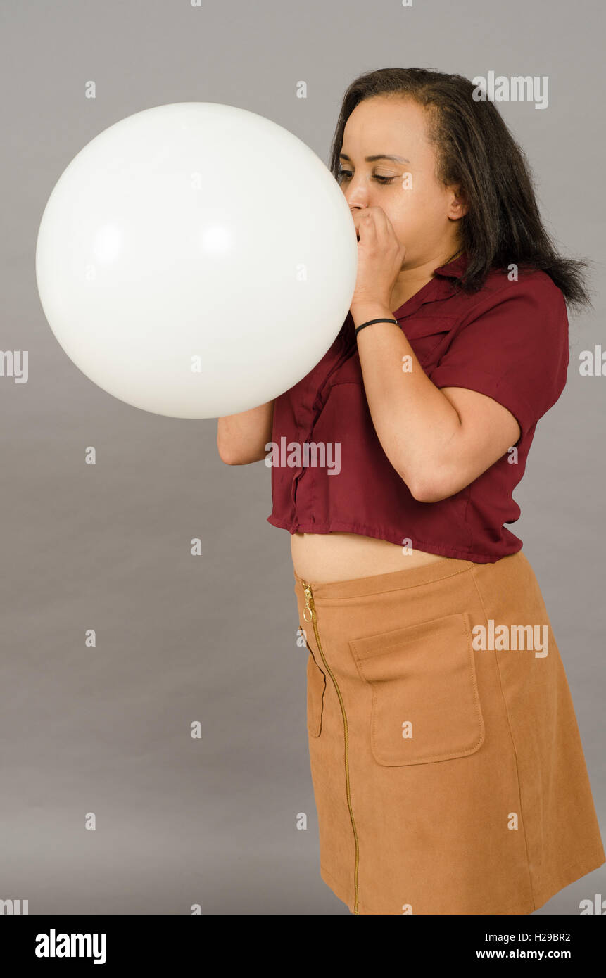 Femmina adulta che soffia su un grande pallone bianco Foto Stock