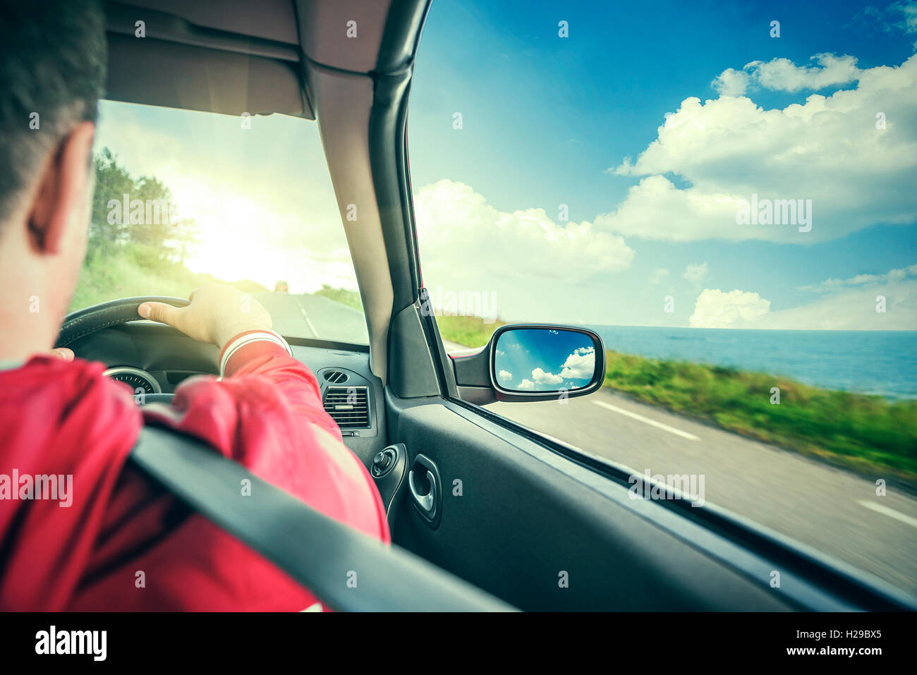 Driver maschio aziona una autovettura convertibile sulla strada del paese dal mare. La vista dalla cabina, vista posteriore, all'interno. Tonica foto. Foto Stock