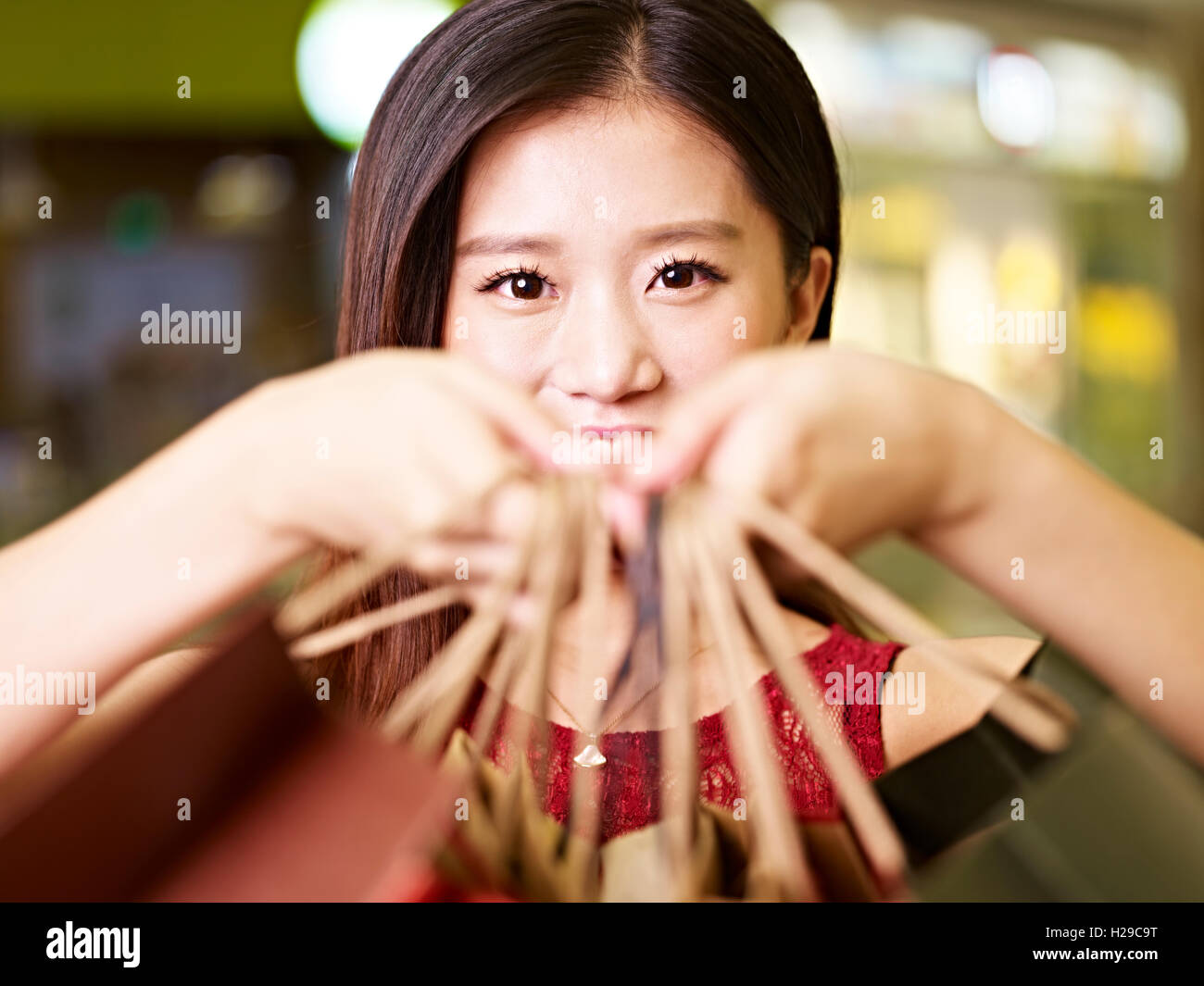 Giovane donna asiatica che mostra ciò che ella ha comprato durante un viaggio di shopping Foto Stock