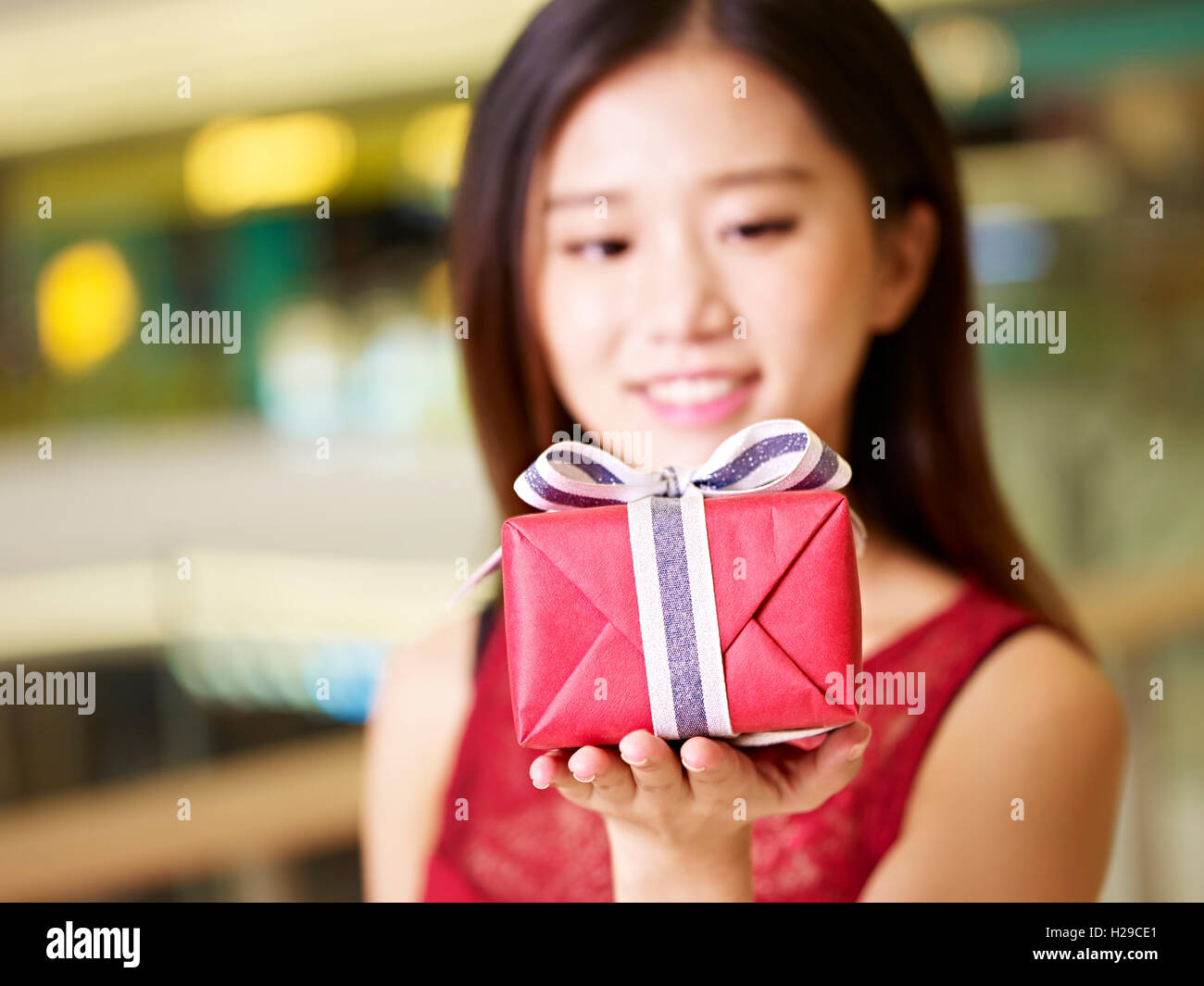 Bella giovane donna asiatica che mostra un regalo avvolto, il fuoco selettivo sulla confezione regalo Foto Stock