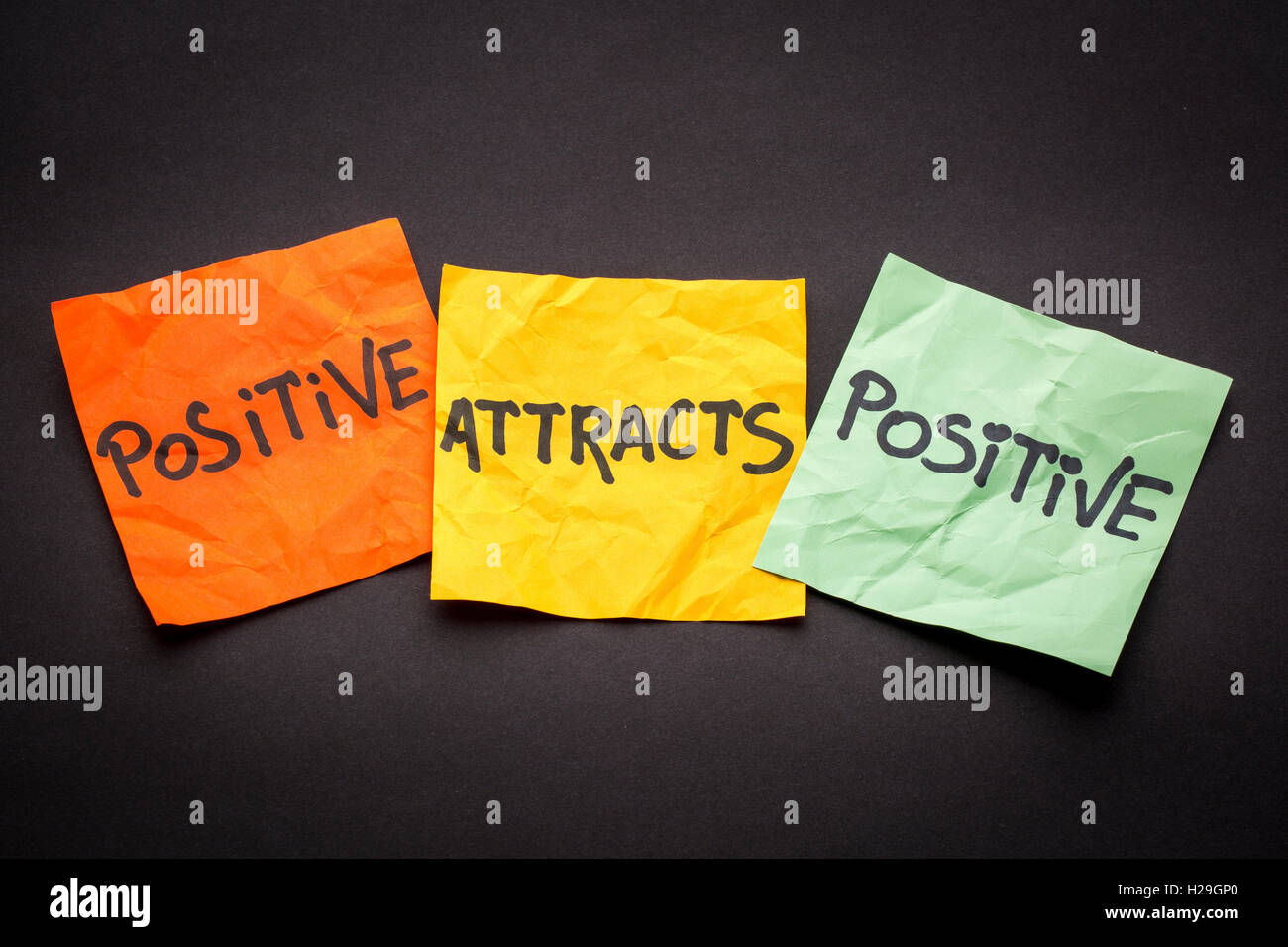 Positivo positivo attira - la legge di attrazione concetto - colorata sticky notes contro la carta nera Foto Stock