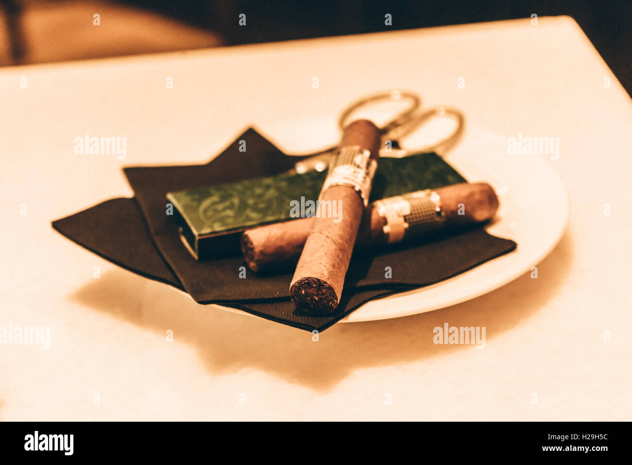 Tonalità seppia sigaro e coltello da caccia su un piatto di portata Foto Stock