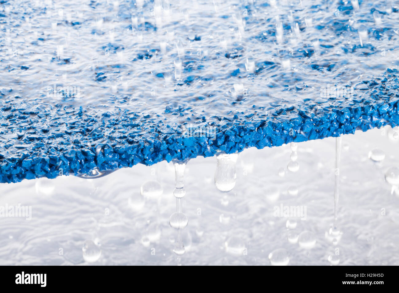 Grumi di gomma superficie con acqua versando attraverso Foto Stock