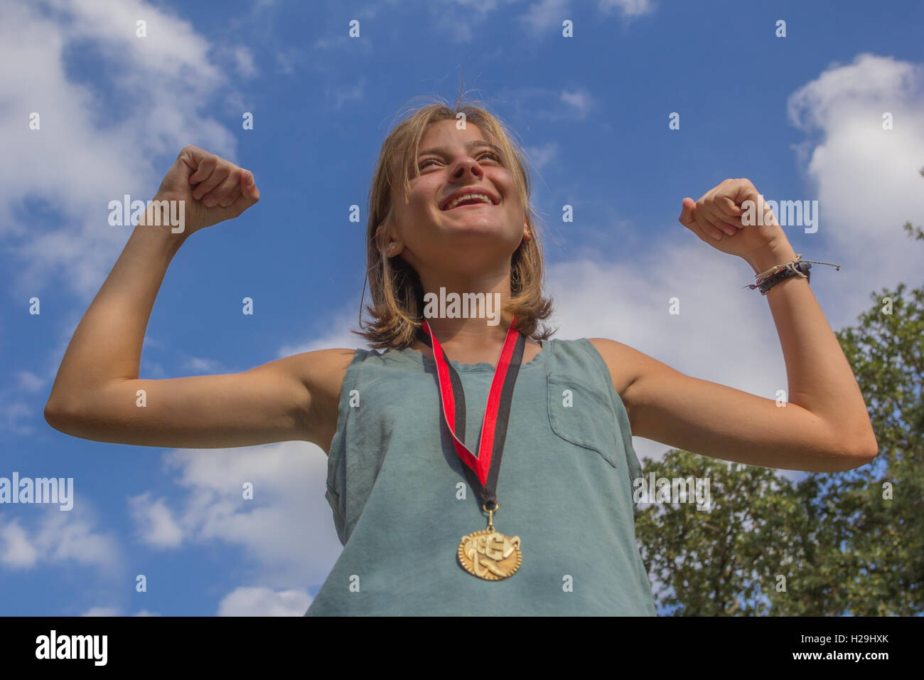 Ragazza che mostra off medaglie d oro contro il cielo blu Foto Stock