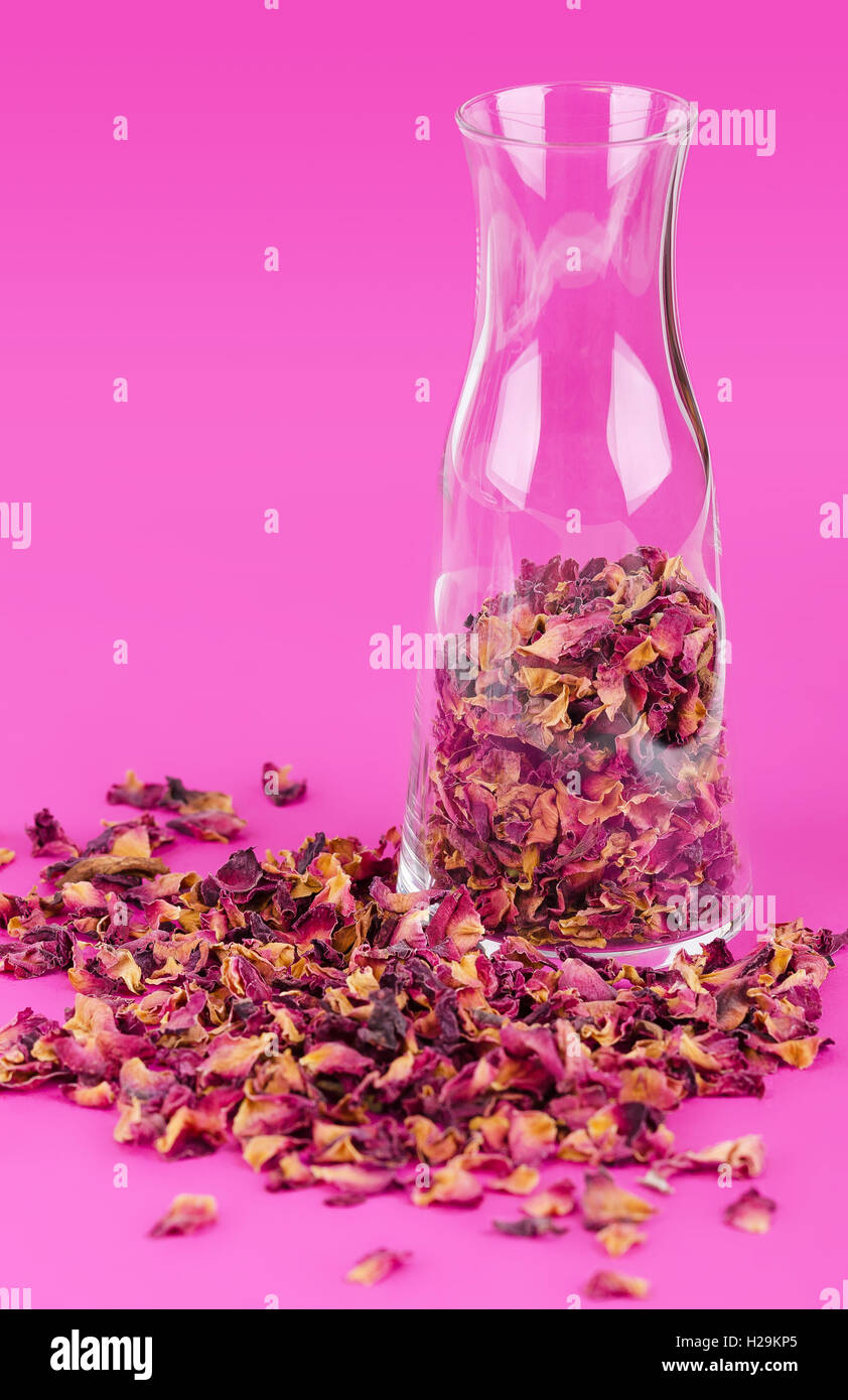 Petali di rosa in un vaso di vetro su rosa. Fiori Secchi, utilizzato per profumi, cosmetici, tè e bagni. Foto Stock