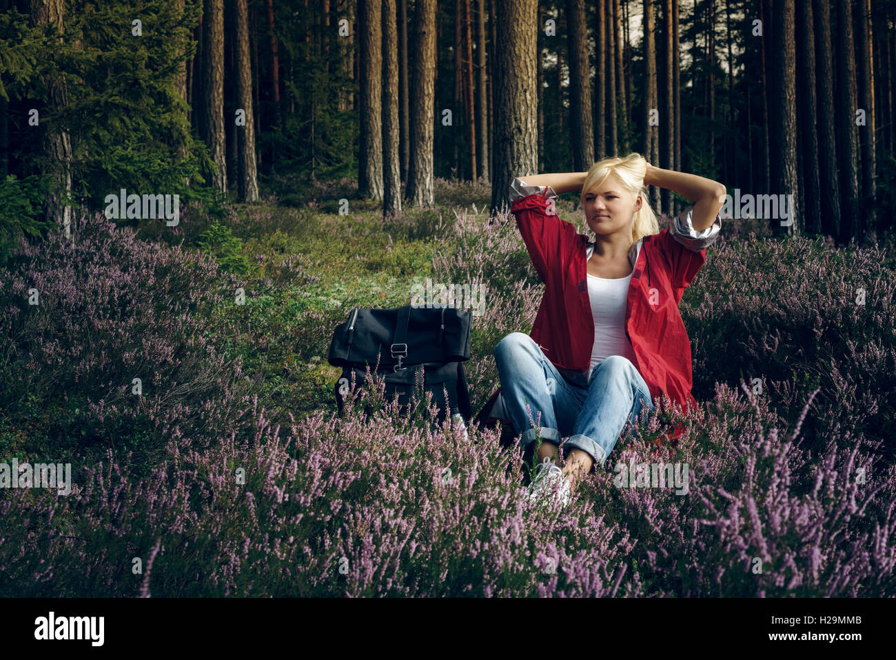 Giovane donna attivo appoggio turistico sul prato nella foresta. Un sano stile di vita attivo concept. Foto Stock