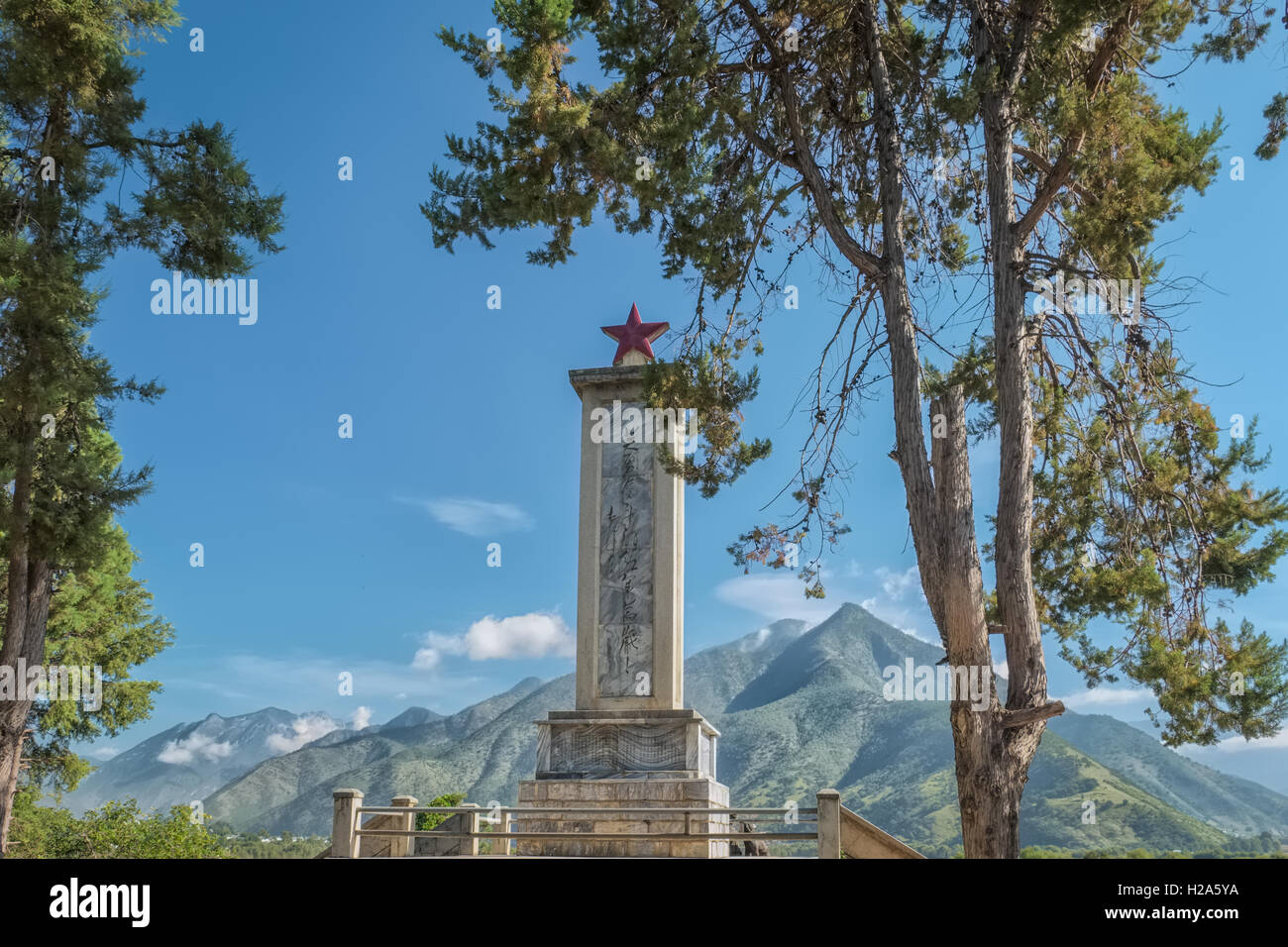 Monumento commemorativo di marzo lungo con stella rossa in cima con montagne come sfondo a Shangri-la, Cina Foto Stock