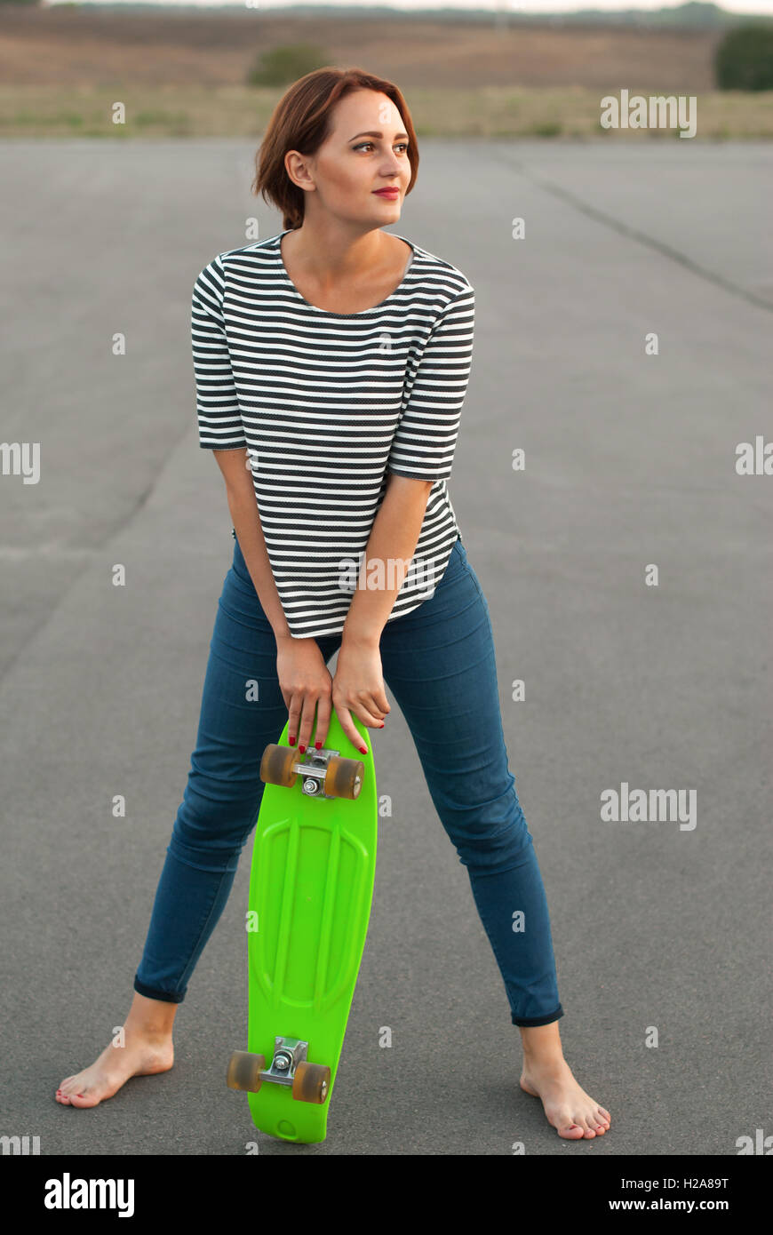 Ragazza con lo skateboard a piedi nudi sull'asfalto. Foto Stock