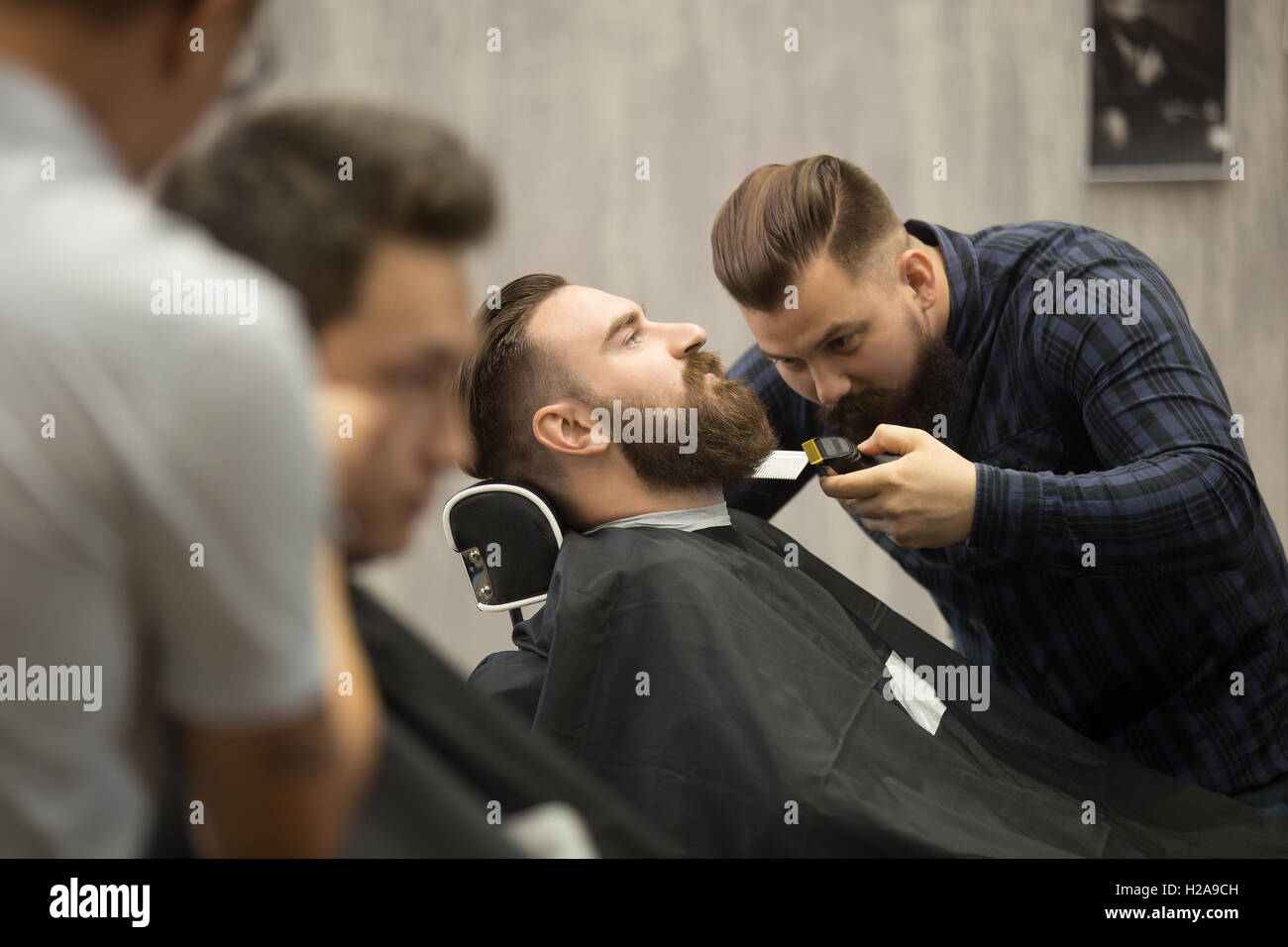 Shot interni del processo di lavoro in barberia. Vista laterale del bel giovane sempre alla moda capelli barba nella moderna barbersho Foto Stock