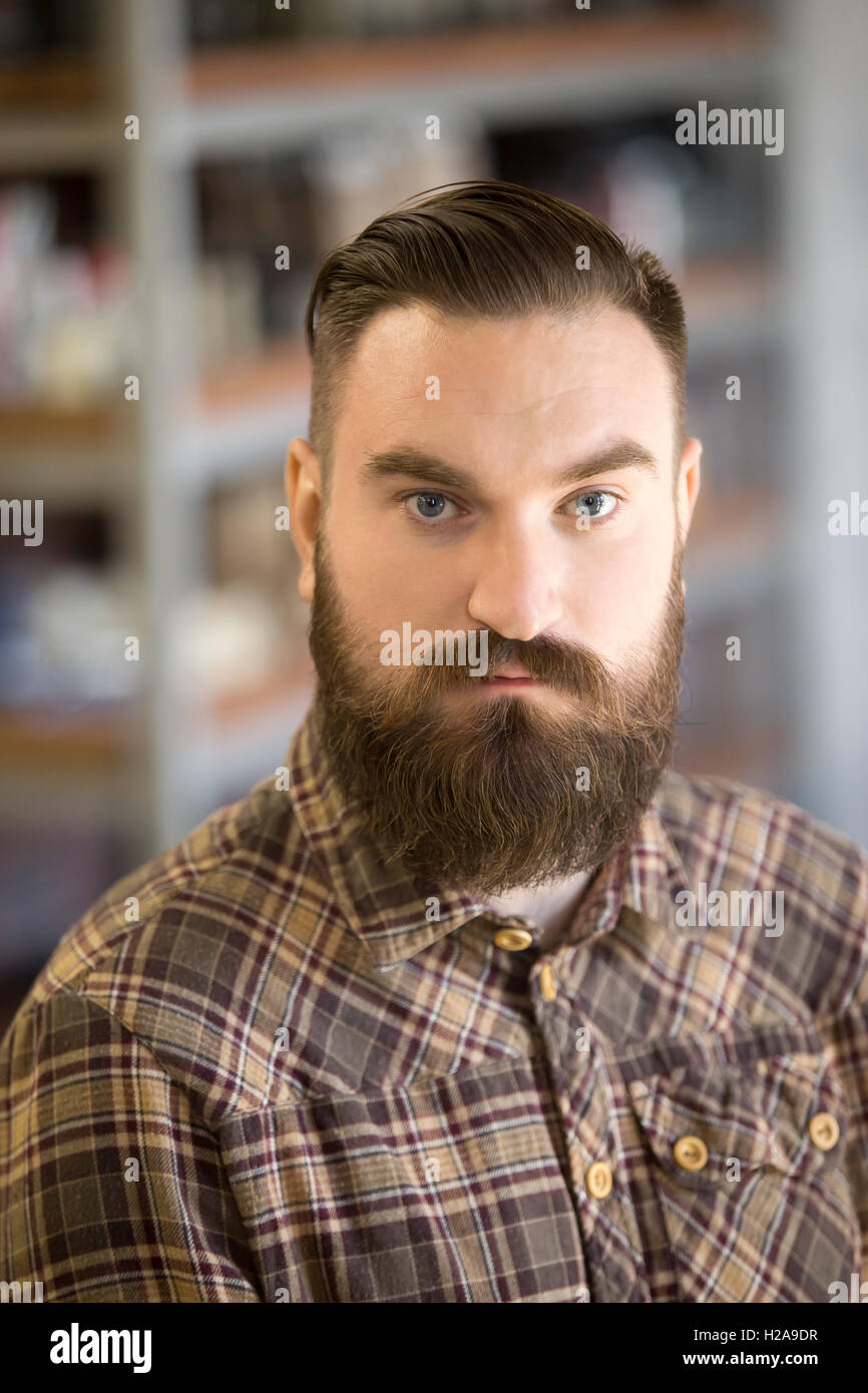 Headshot Ritratto di giovane serio con lunga barba e baffi. Bel uomo barbuto in posa con mani incrociate sul petto Foto Stock