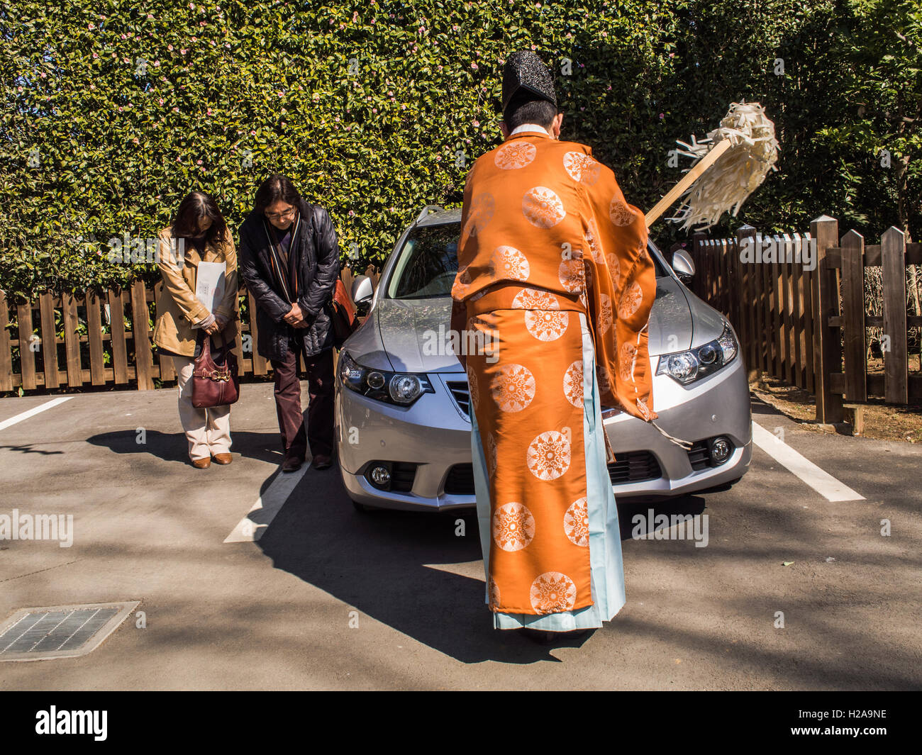 Lo Shintoismo rituale. Hikawa Shrine, Omiya. Due donne giapponesi archetto come un sacerdote scintoista esegue il rituale di purificazione sulla loro auto. Foto Stock