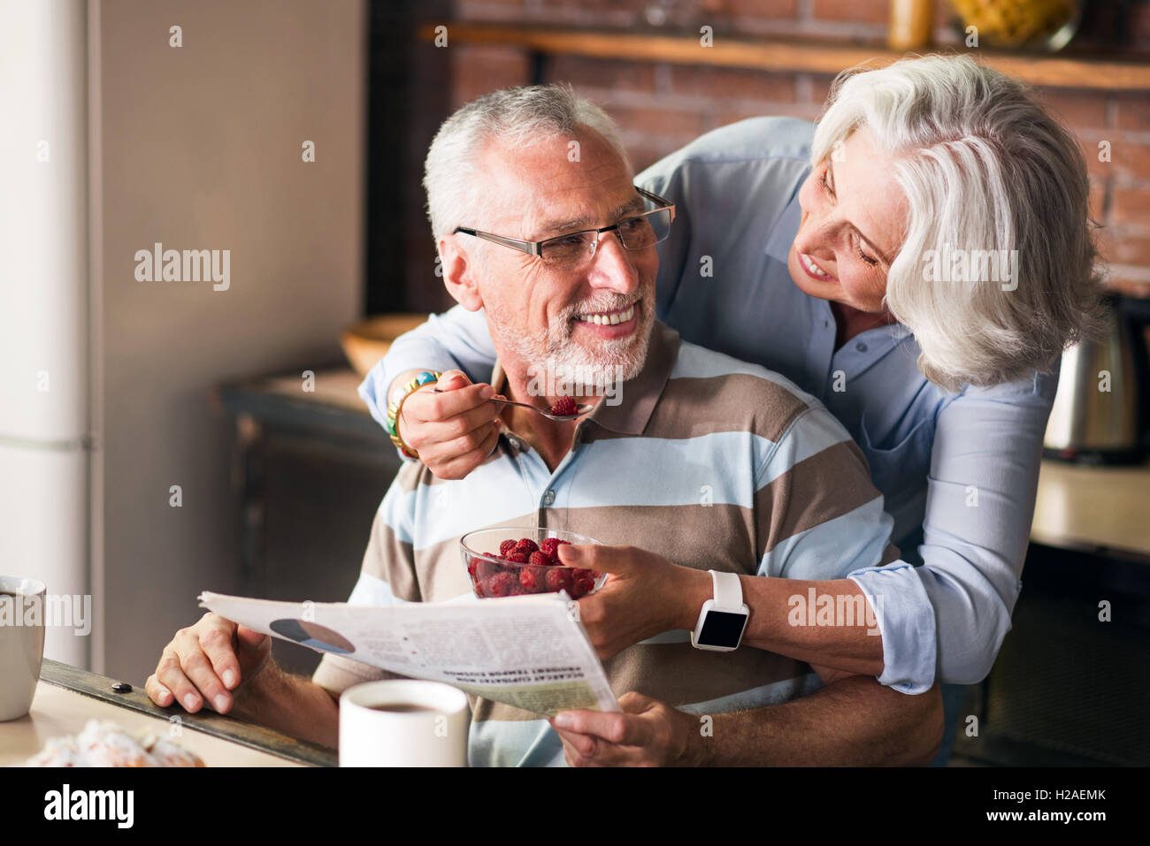 Felice dei nonni che parla e ride mentre mangiando in cucina Foto Stock