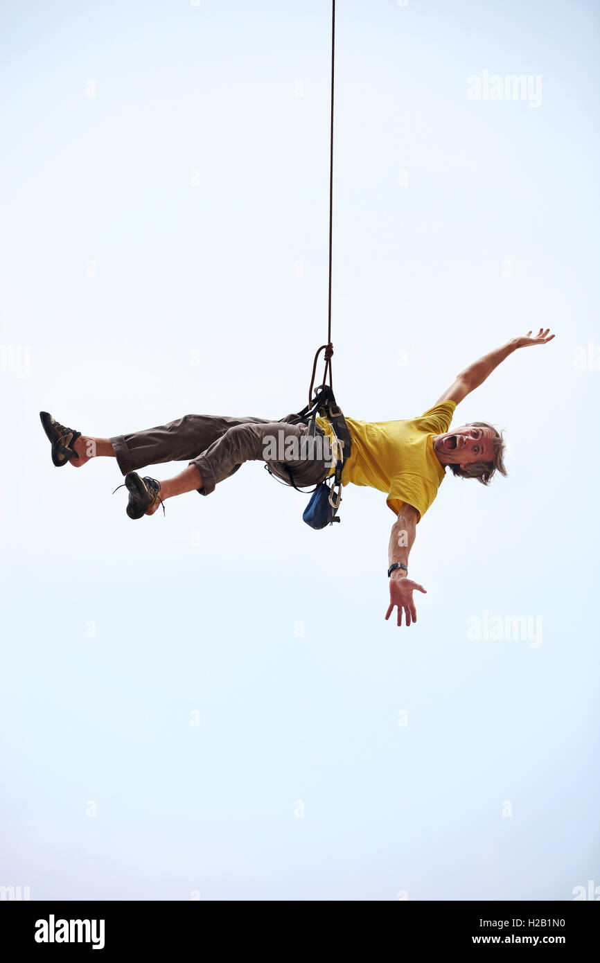 Felice rocciatore appeso sulla corda Foto Stock