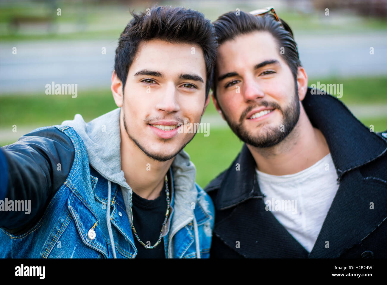 Due giovani uomini tenendo selfie mentre ci si trova all'esterno, il punto di vista della telecamera stessa Foto Stock