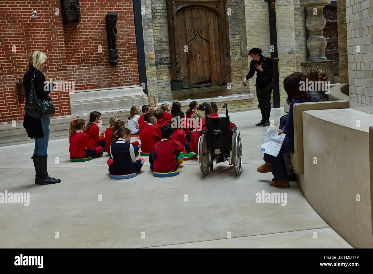 Londra, di un gruppo di alunni seduta sul pavimento ascoltare la guida in Victoria e Albert Museum è il più grande museo di arti decorative. Foto Stock