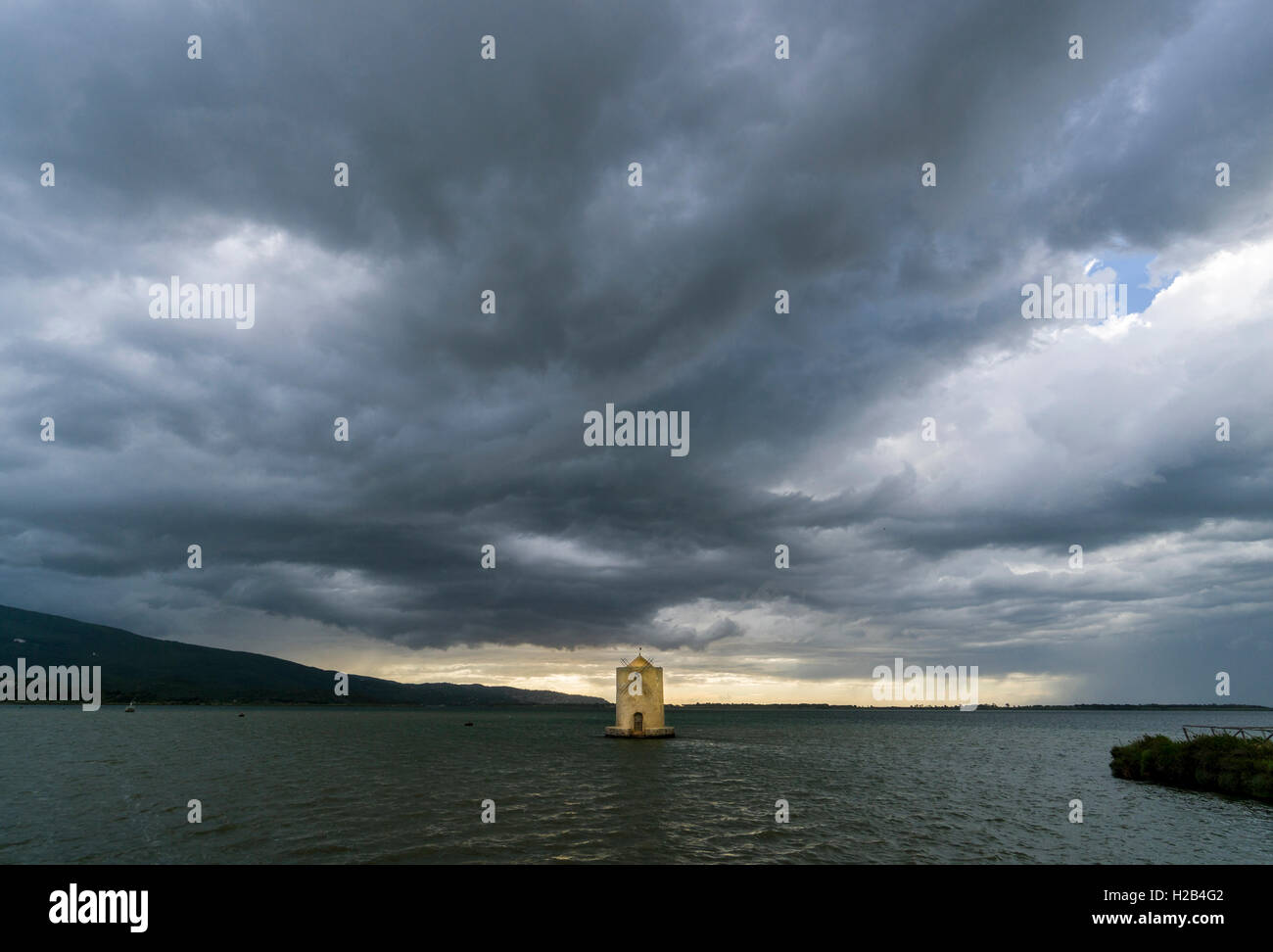 Il mulino a vento di spagnolo in laguna, cielo scuro dietro, Orbetello, Toscana, Italia Foto Stock