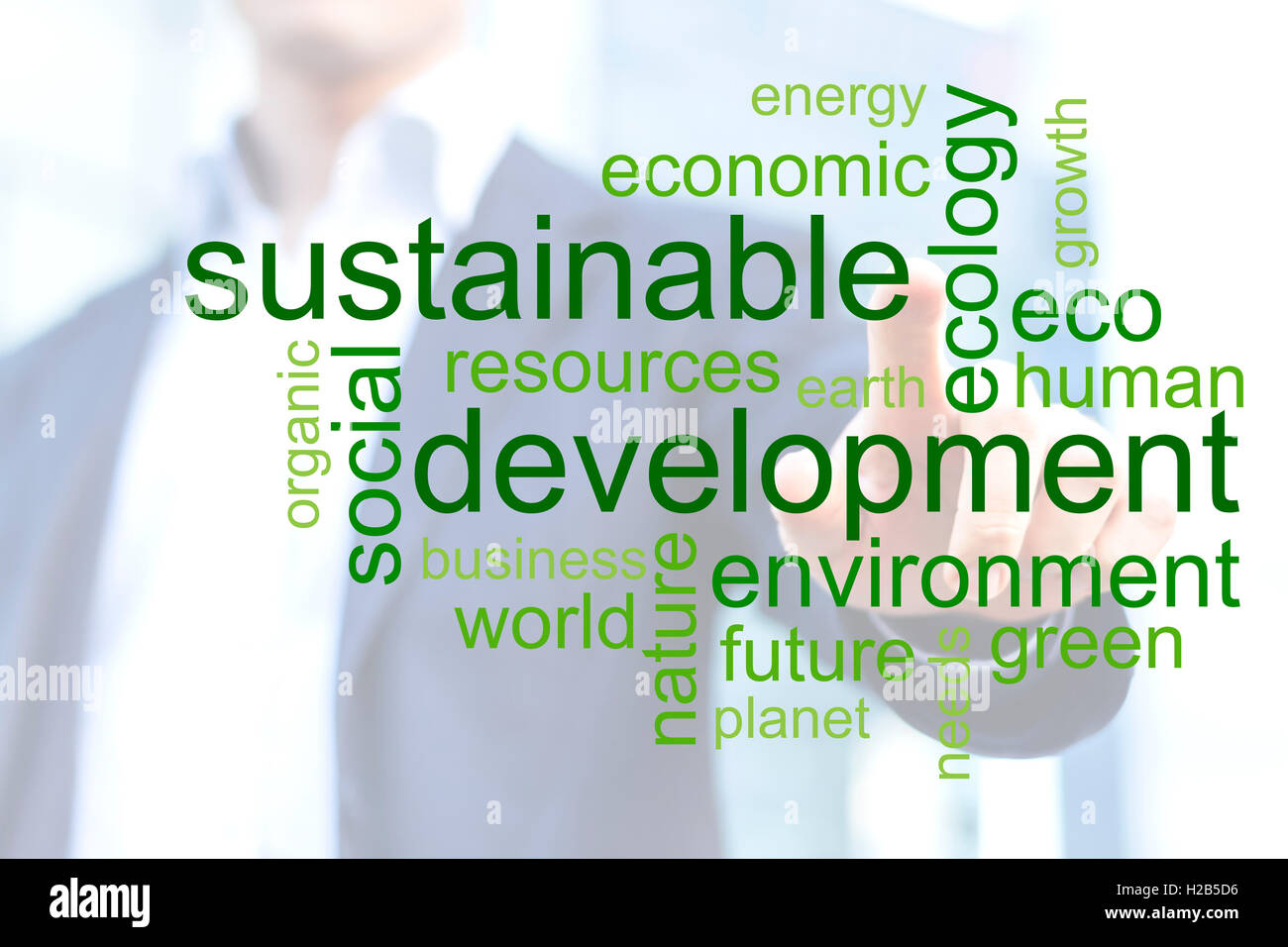 Imprenditore toccando green tag cloud circa lo sviluppo sostenibile con edifici per uffici in background Foto Stock