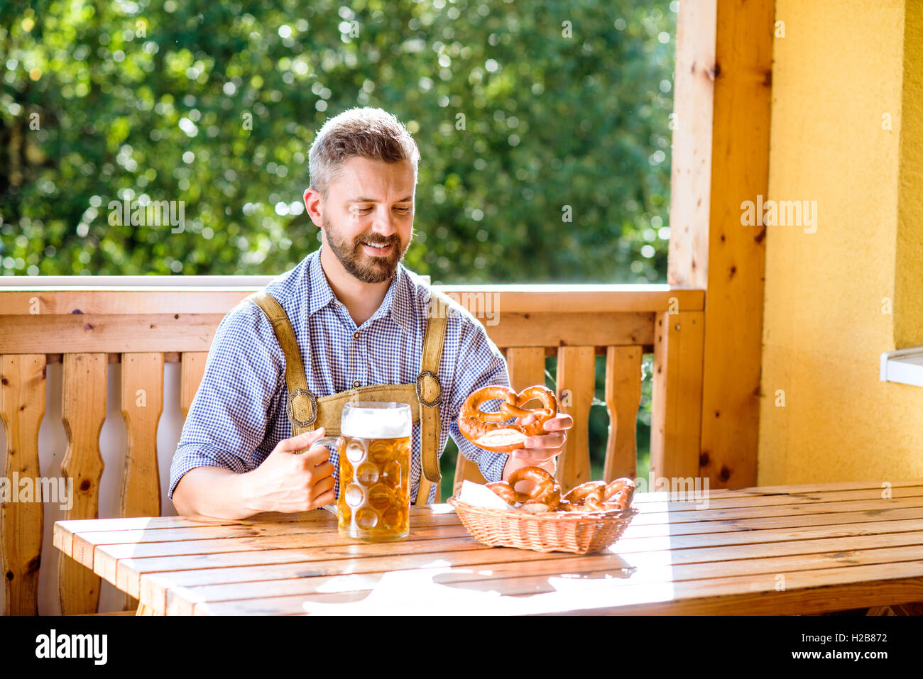 Uomo in tradizionali abiti bavarese con birra e salatini Foto Stock