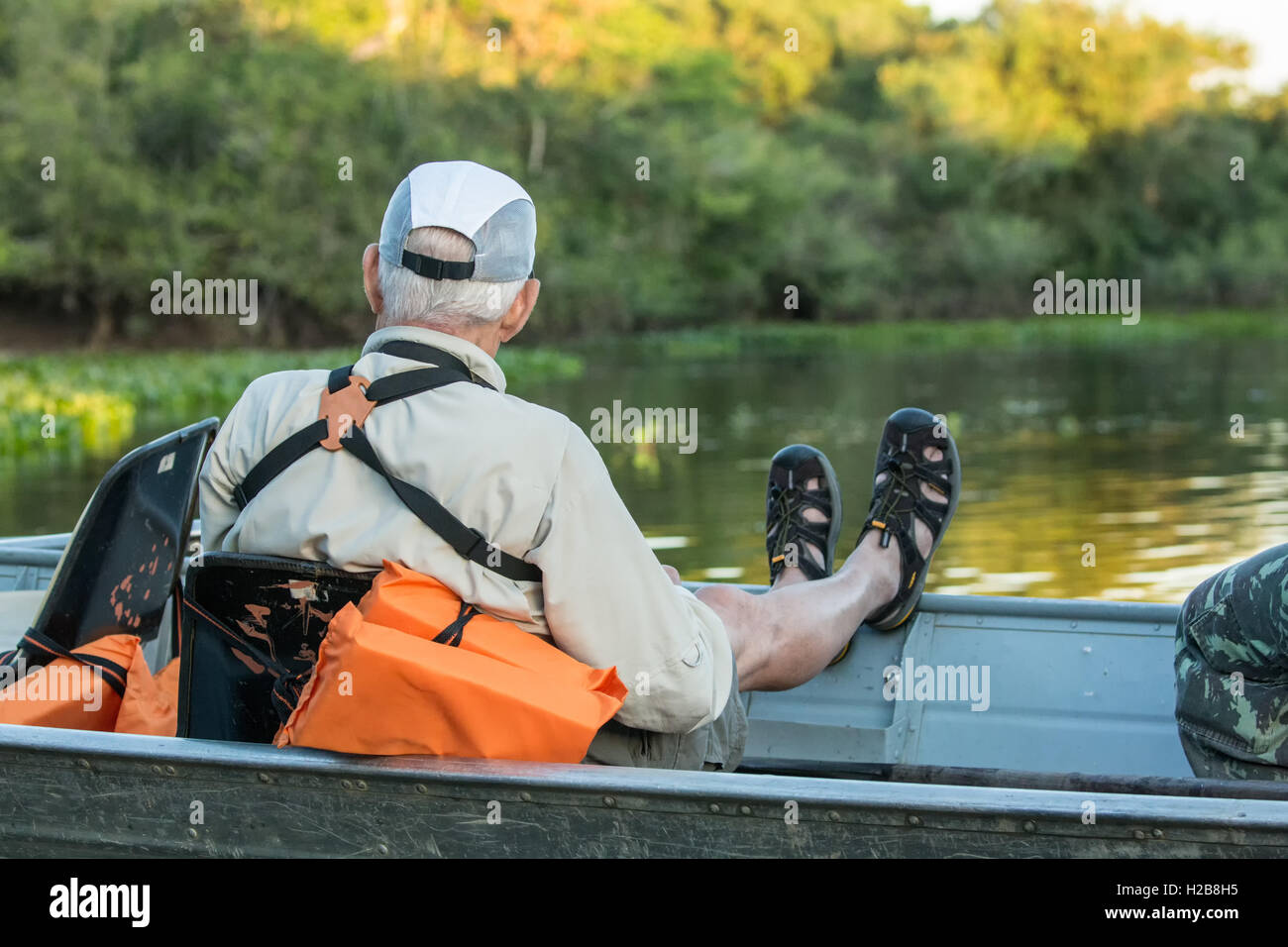 Maschio di turisti in un tour in barca in attesa di una Jaguar per spostare su un fiume safari nella zona Pantanal del Brasile. Foto Stock