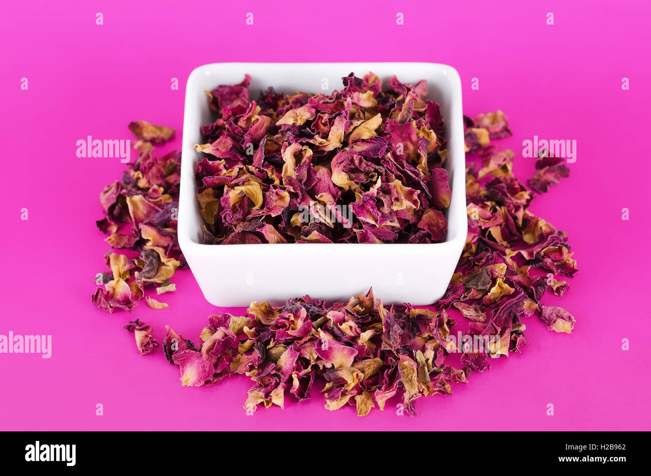 Petali di rosa in un vaso bianco su sfondo rosa. Fiori Secchi, utilizzato per profumi, cosmetici, tè e bagni. Foto Stock