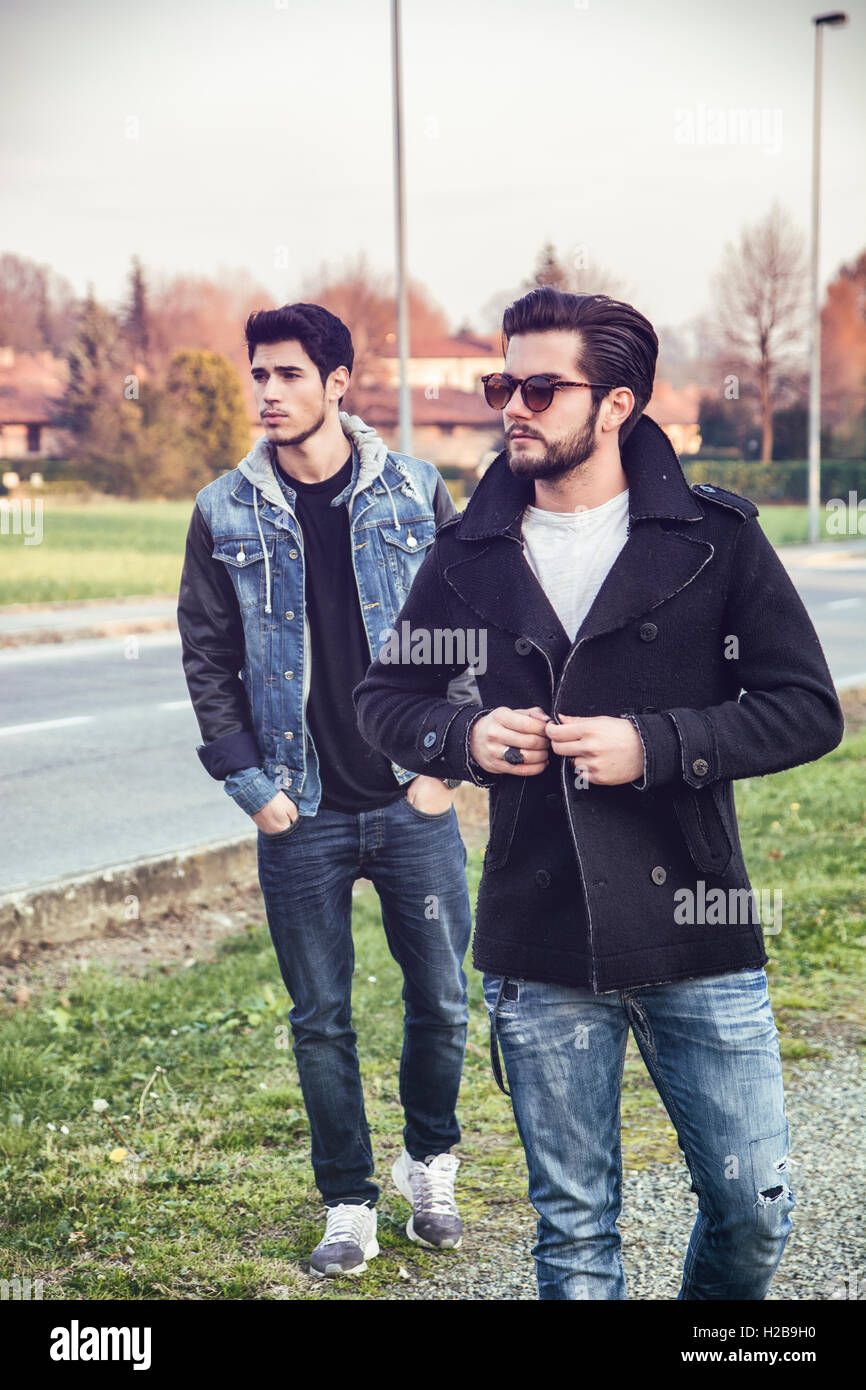 Due graziosi alla moda casual giovani uomini, 2 amici, in un parco urbano a piedi e chiacchierare insieme Foto Stock