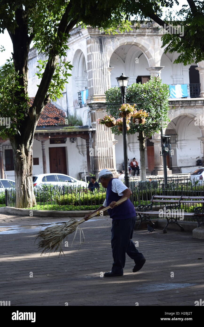 Pubblico spazzatrice pulizia del parco centrale di Antigua Guatemala con la scopa tradizionale Foto Stock
