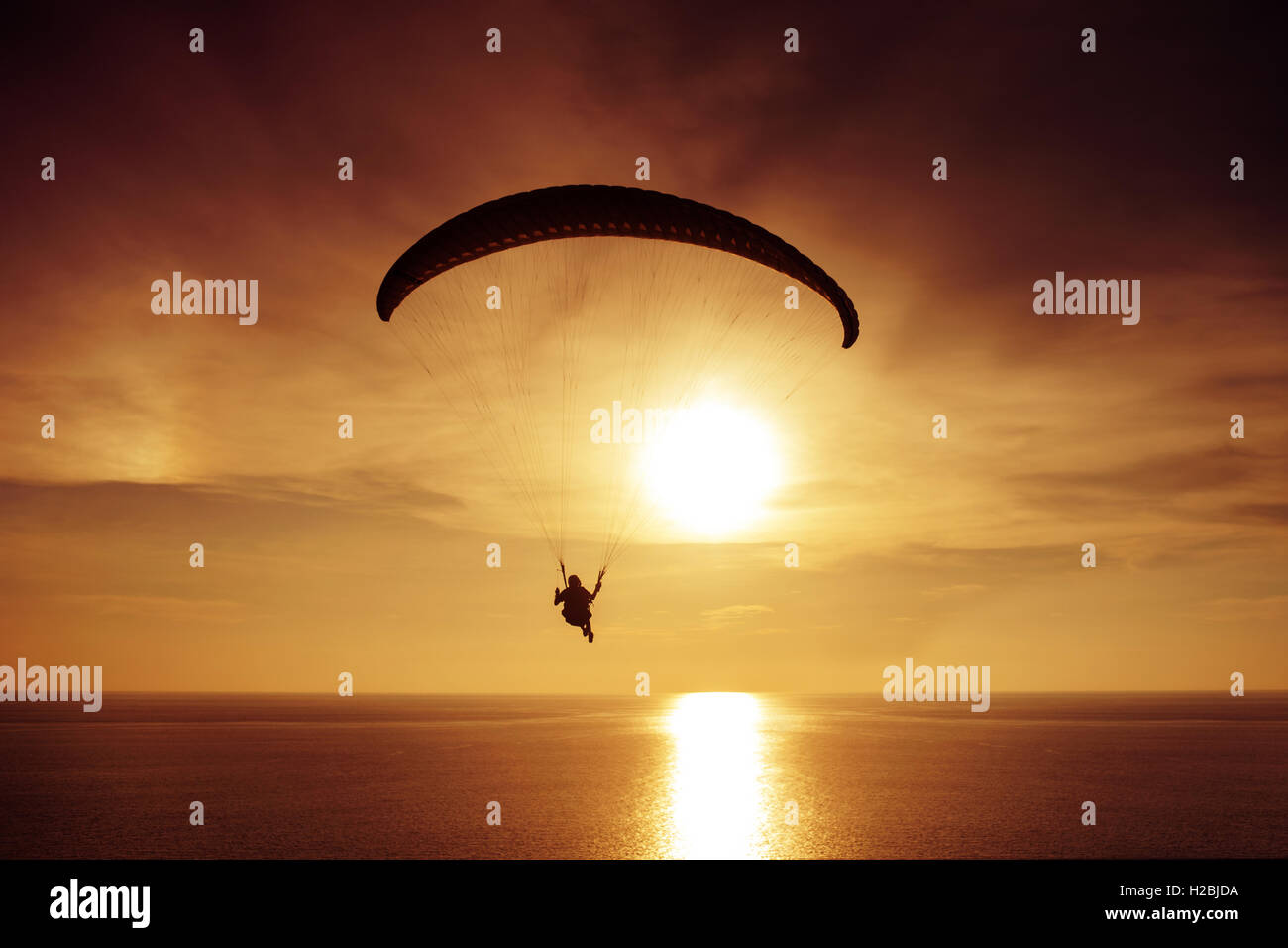 Silhouette di un paracadutista sul tramonto e il mare sullo sfondo Foto Stock