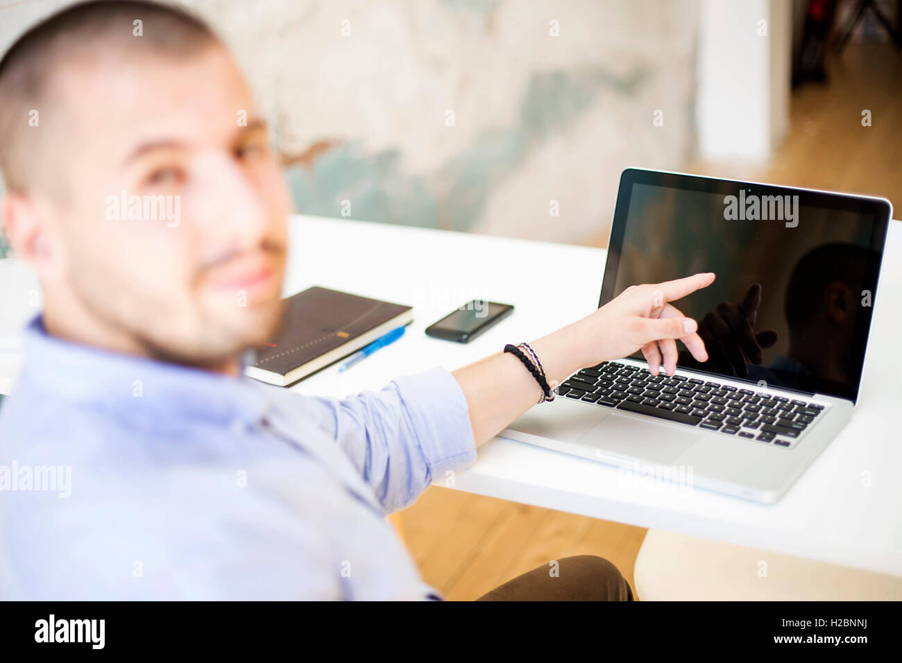 Giovane uomo che lavora sul computer portatile in ufficio egli Foto Stock