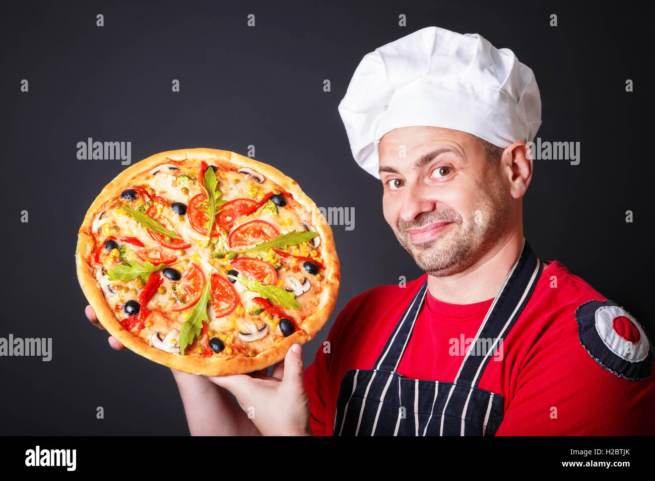 Ritratto di felice attraente cook con una pizza nelle sue mani Foto Stock