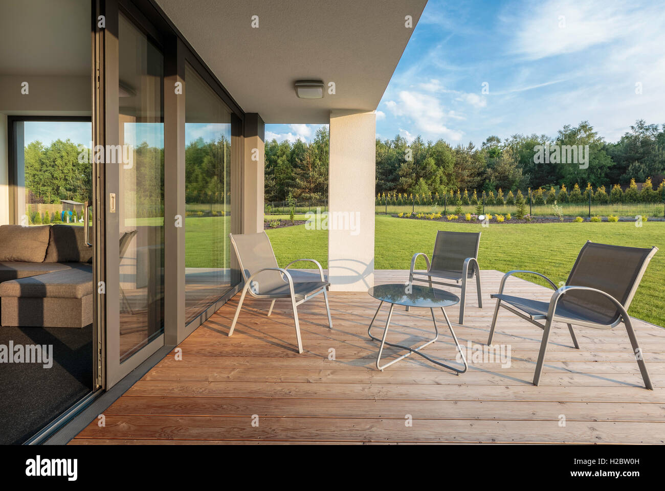 Patio ed elegante con pavimento in legno e vista sul giardino, patio semplice insieme di mobili Foto Stock