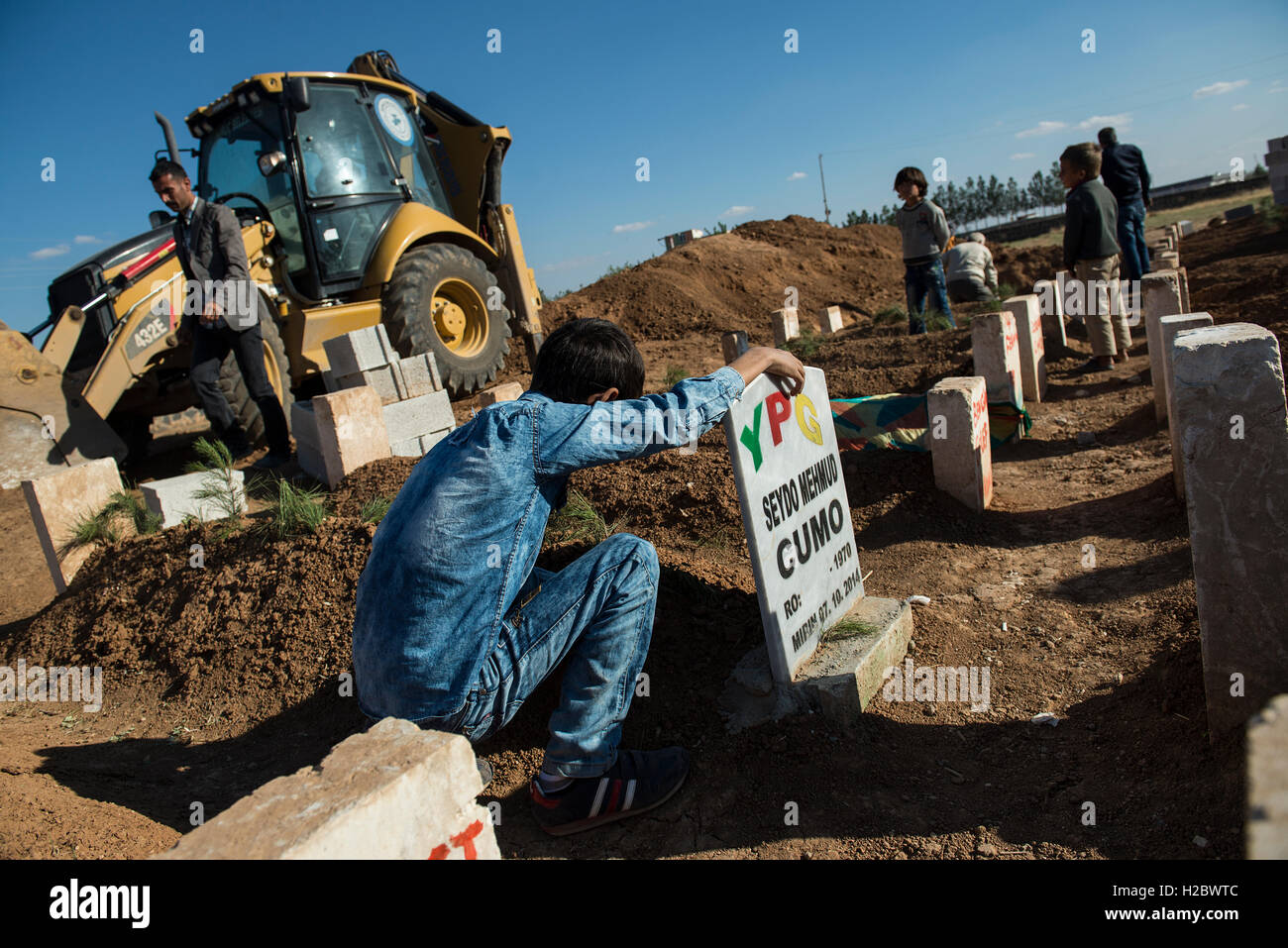 Un ragazzino curdo sorge accanto alla tomba di suo padre, morto nell'assedio della città siriana di Kobani, durante il combattimento contro uno Stato islamico forze, presso la città turca di Suruc, vicino al confine Turkish-Syrian. Migliaia di curdi che erano stati costretti ad abbandonare la città siriana di Kobani, che è sotto assedio da parte di uno Stato islamico forze. La maggior parte di loro vivono in campi per rifugiati nella città turca di Suruc. Foto Stock