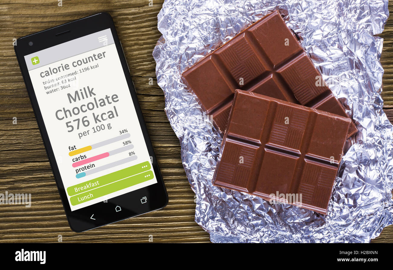 Calorie Counter concetto concetto - telefono cellulare con contatore di caloria app sullo schermo e di cioccolato al latte. Tavolo in legno come backg Foto Stock