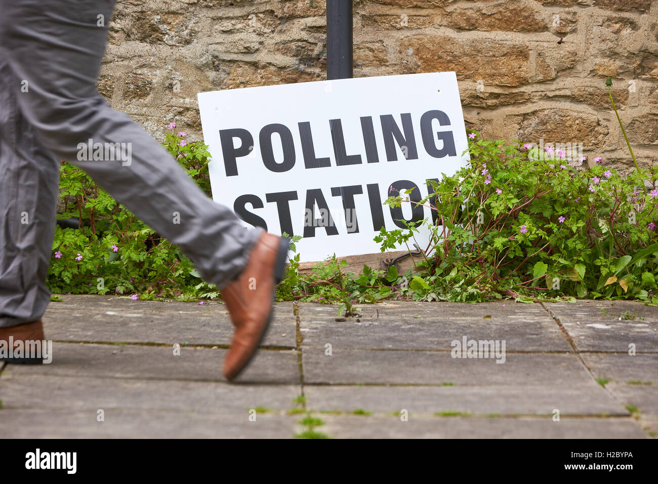 Un uomo cammina davanti ad una stazione di polling sign in Oxford il giorno del 2015 elezioni generali Foto Stock