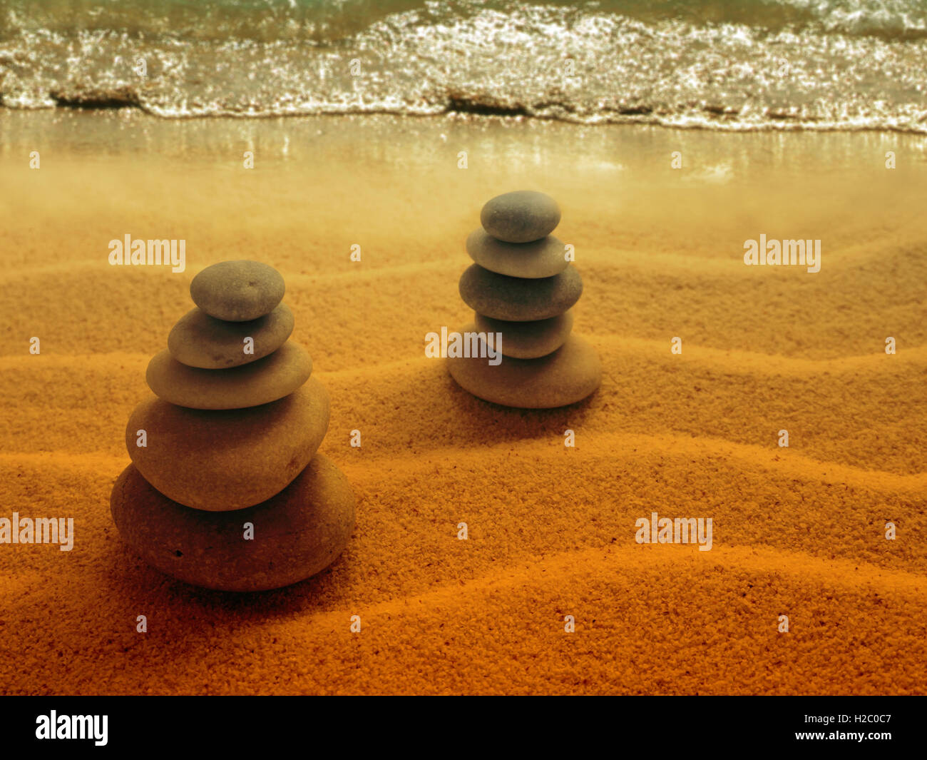 Piramide di pietre sulla spiaggia al tramonto Foto Stock