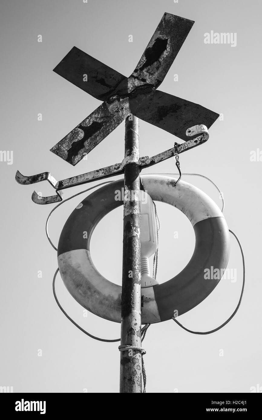 Vecchio arrugginito a forma di croce segno di navigazione con salvagente, in bianco e nero in stile retrò foto Foto Stock