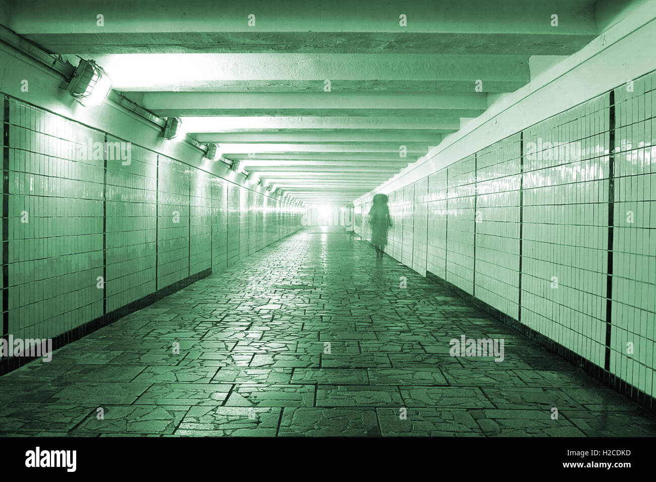 Allegoria mistica immagine: tunnel pedonale con pavimento in pietra con spia luminosa in corrispondenza del suo bordo in remoto e silhouette di donna. Foto Stock