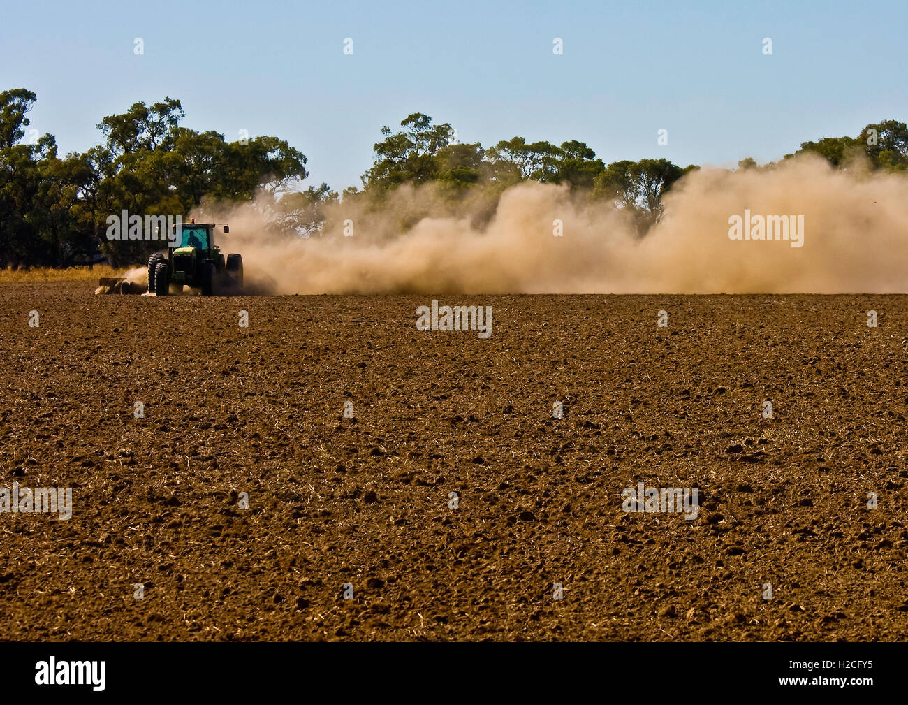 Il contadino si solleva nuvole di polvere come egli ara il suo siccità-campo interessato Foto Stock