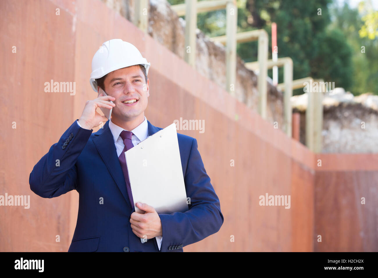 Architetto in cantiere utilizzando il telefono cellulare Foto Stock