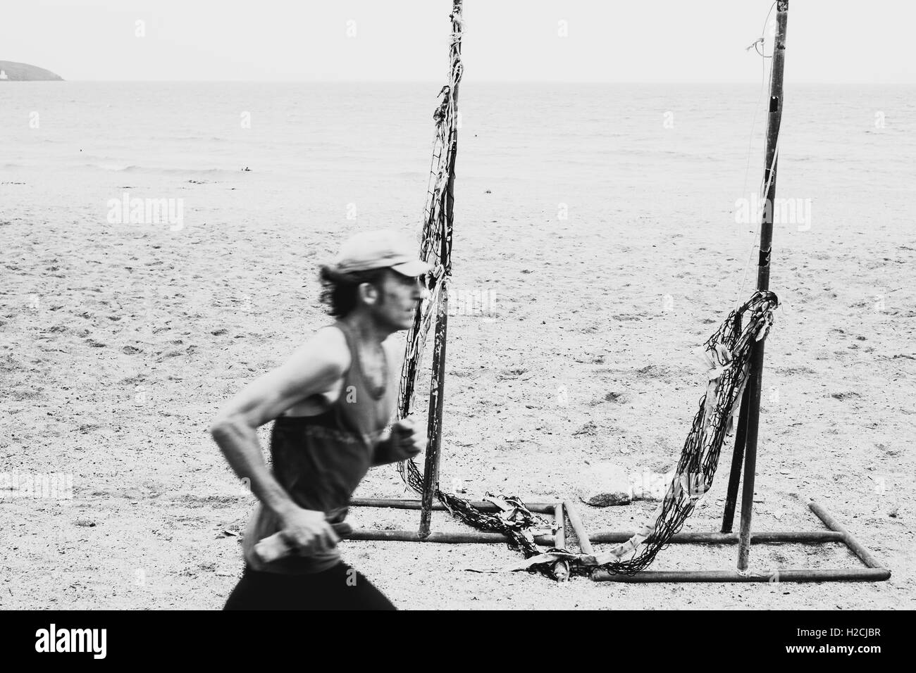 Un uomo che corre lungo il passato a Gyllyngvase Beach, Falmouth, Cornwall. Foto Stock