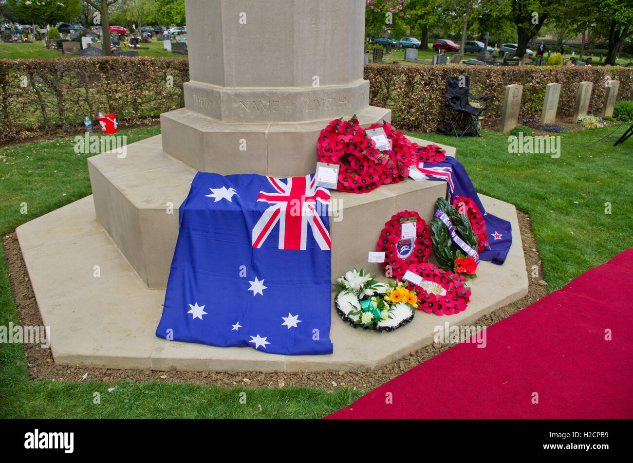 Base di una croce di sacrificio con bandiere e corone di fiori di papavero in occasione del centenario di Anzac Day, Northampton, Regno Unito Foto Stock